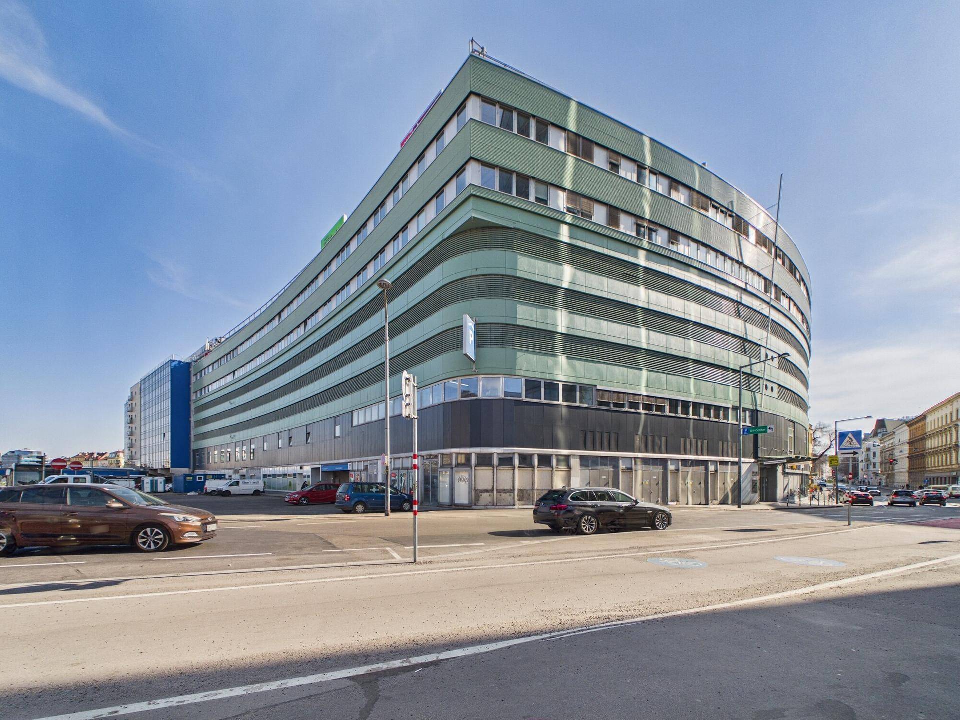 Modernes Geschäftsgebäude mit geschwungener Fassade und vielen Fenstern in urbaner Umgebung.