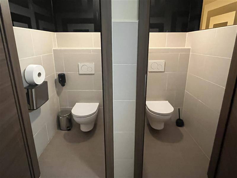 Zwei separate Toilettenkabinen mit modernen Wand-WCs und hellen Fliesen.