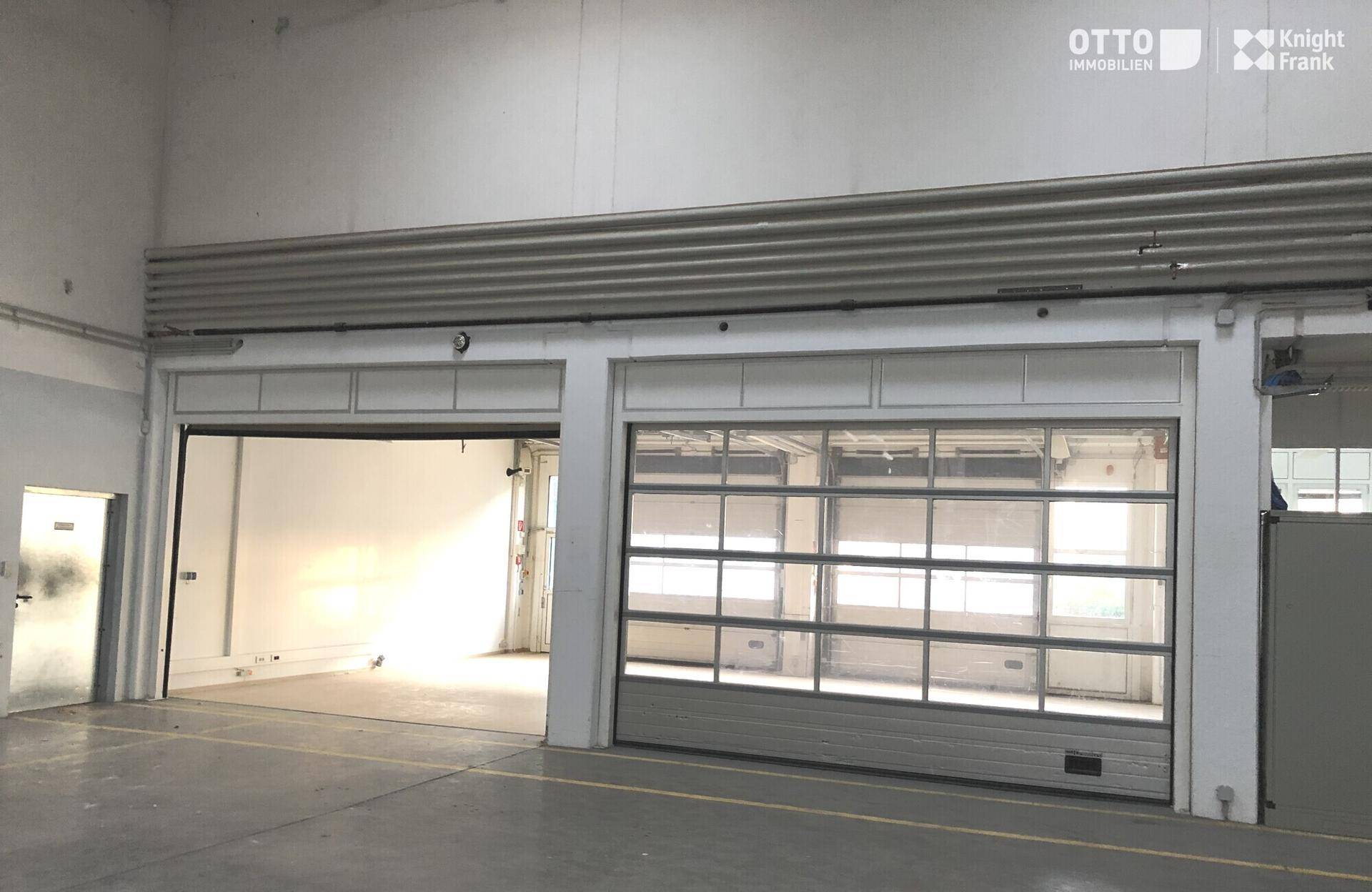 Große Industrietore mit Glaspaneelen ermöglichen den Zugang und bringen natürliches Licht in die Lagerhalle.