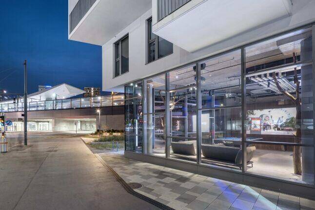 Moderne Gebäudefassade bei Dämmerung mit großen Glasfenstern, die den Innenbereich zeigen.