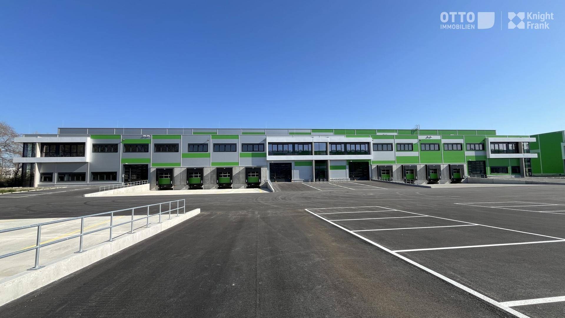 Außenansicht des modernen Logistikzentrums mit zahlreichen Laderampen und großzügigen Parkflächen für Fahrzeuge.