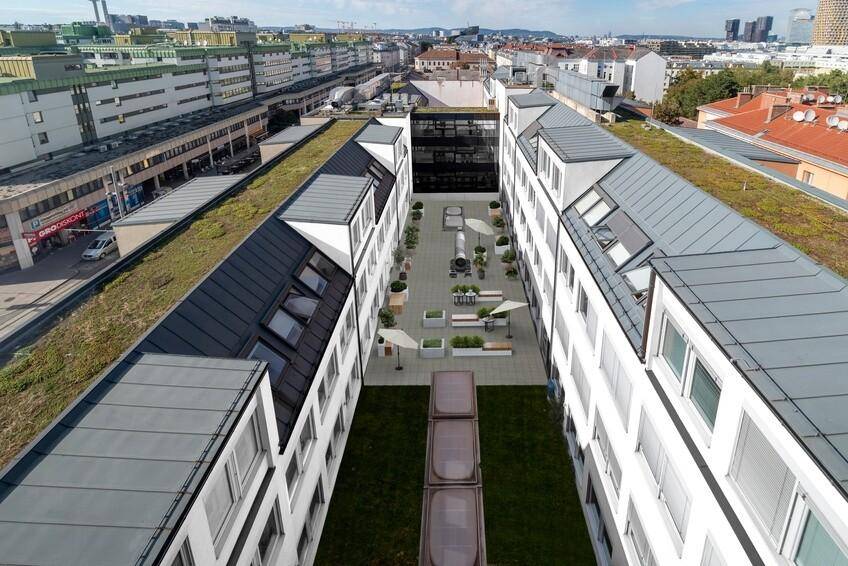 Weitläufige Luftaufnahme eines Gebäudekomplexes mit begrünten Dächern und einem zentralen Innenhof.