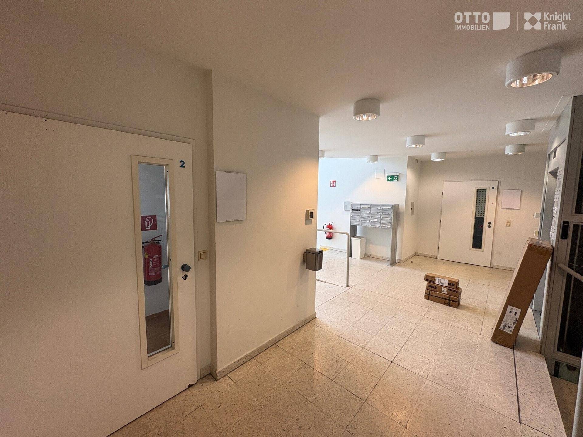 Geräumiger Eingangsbereich mit Fliesenboden, Briefkästen und Zugang zum Aufzug.