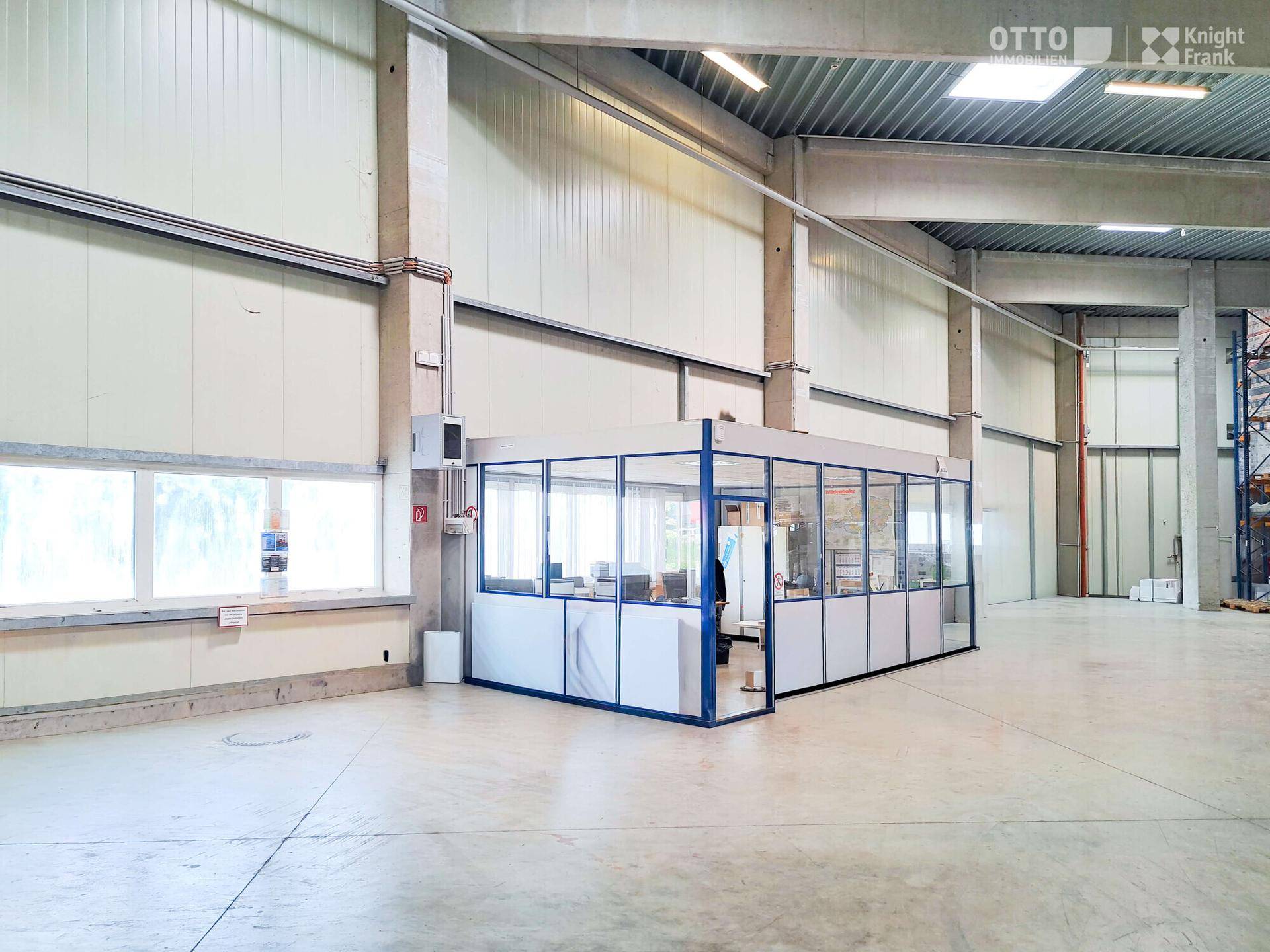 Geräumige Lagerhalle mit integriertem Glasbüro und hohen Decken, bietet flexible Arbeitsbereiche.