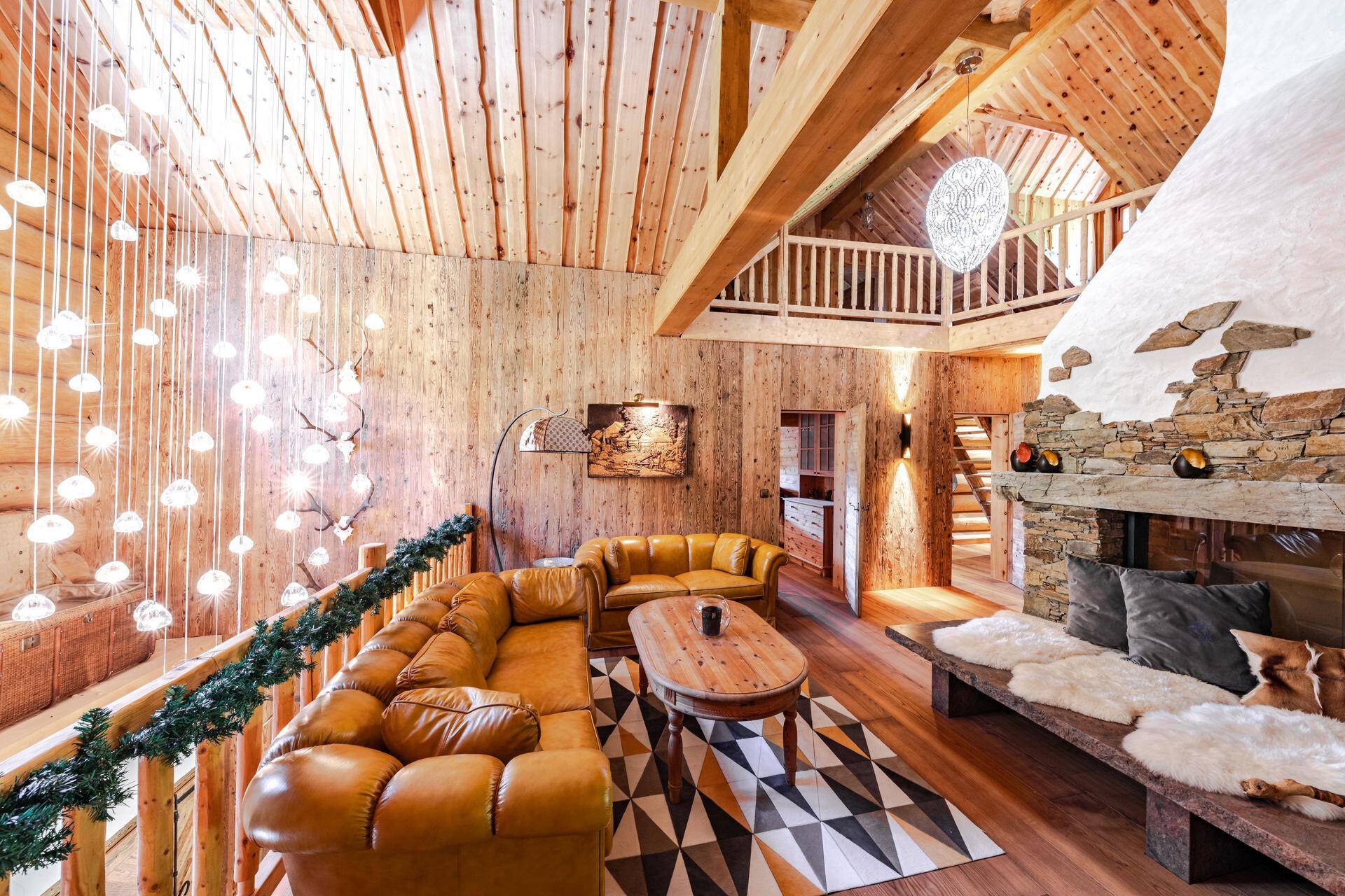 Großzügiges Wohnzimmer mit hohen Holzdecken, Kamin und gemütlicher Ledercouch.