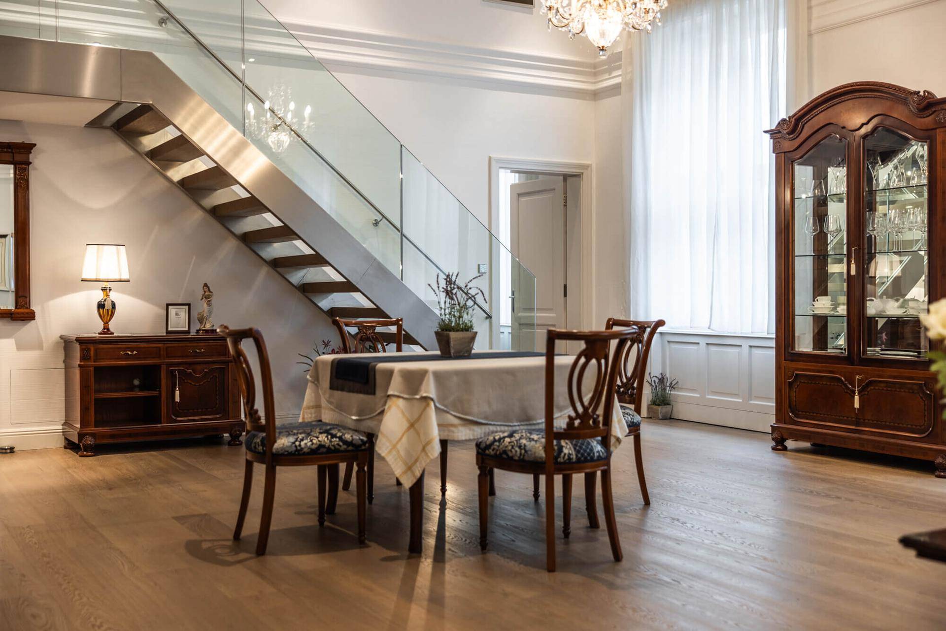 Eleganter Essbereich mit Holztisch, Stühlen und Blick auf die moderne Glastreppe.