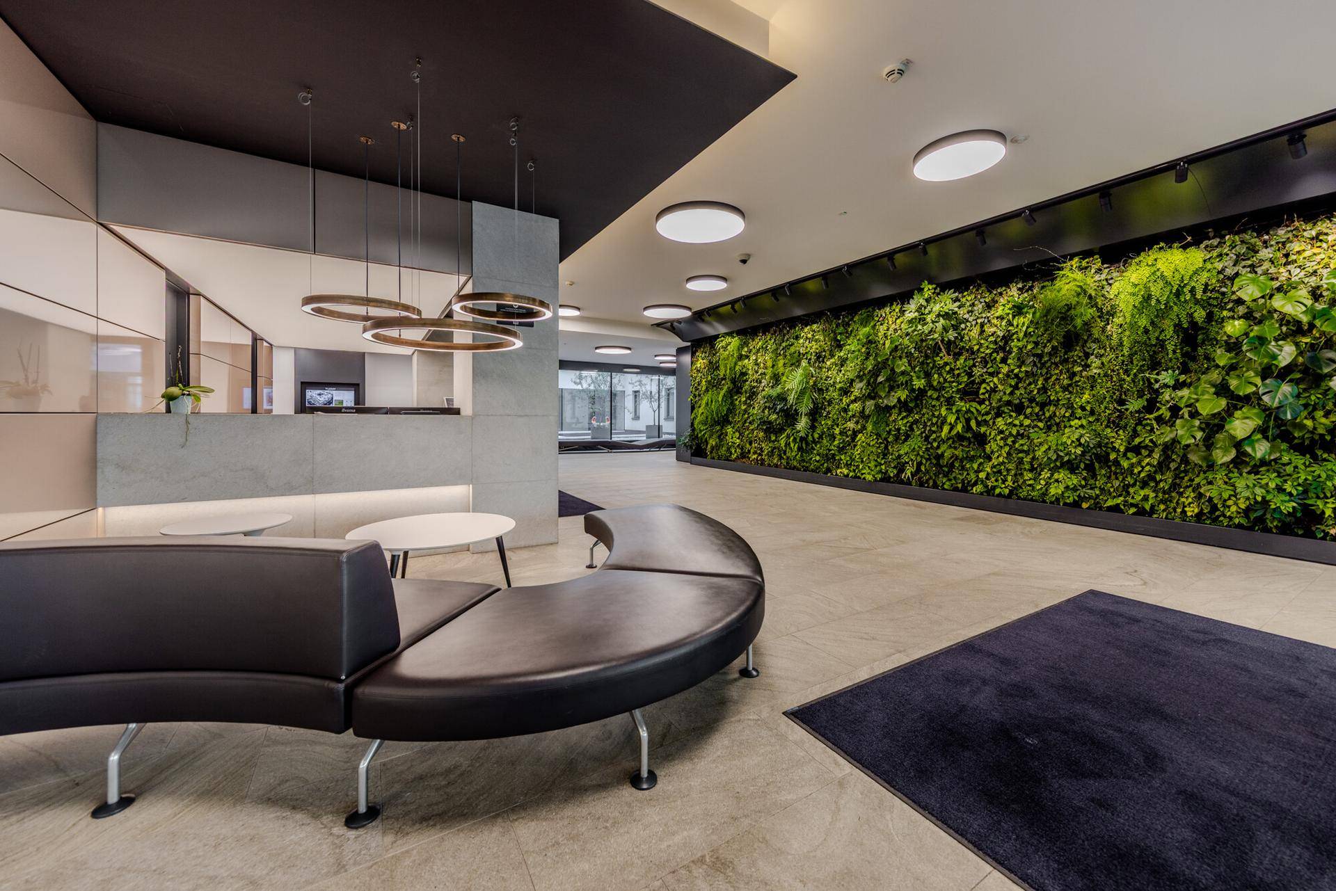 Moderne Lobby mit einer beeindruckenden grünen Wand, stilvollen Sitzgelegenheiten und zeitgemäßer Beleuchtung.