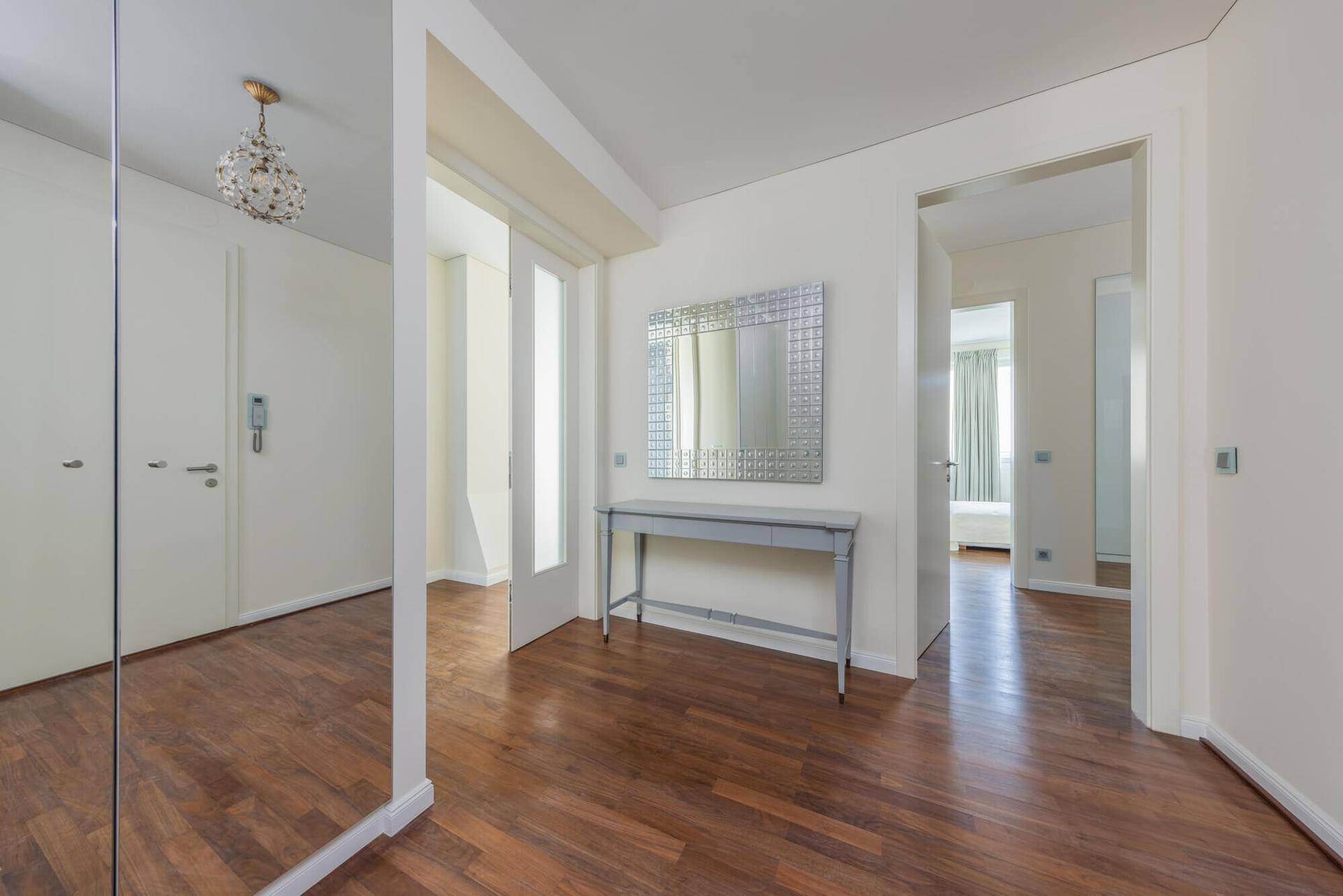 Heller Flur mit Holzboden, großem Spiegel und Zugang zu verschiedenen Räumen der Wohnung.