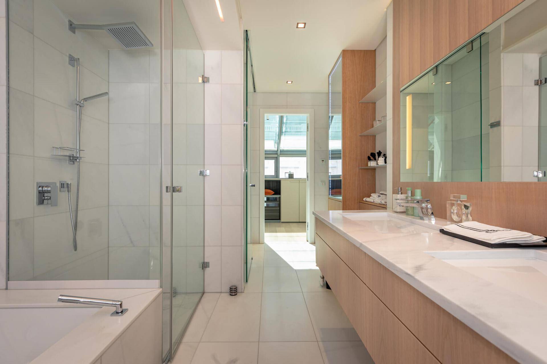 Modernes Badezimmer mit Doppelwaschbecken, begehbarer Dusche und hellen Marmorfliesen.
