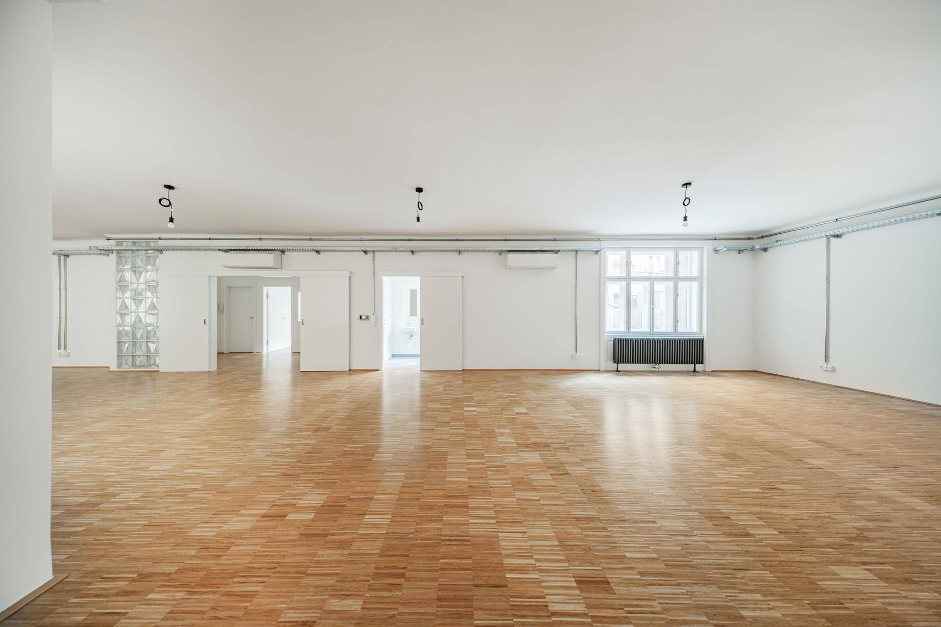 Weitläufiger Innenraum mit hellem Parkettboden, hohen Decken und Schiebetüren, ideal für flexible Nutzung.