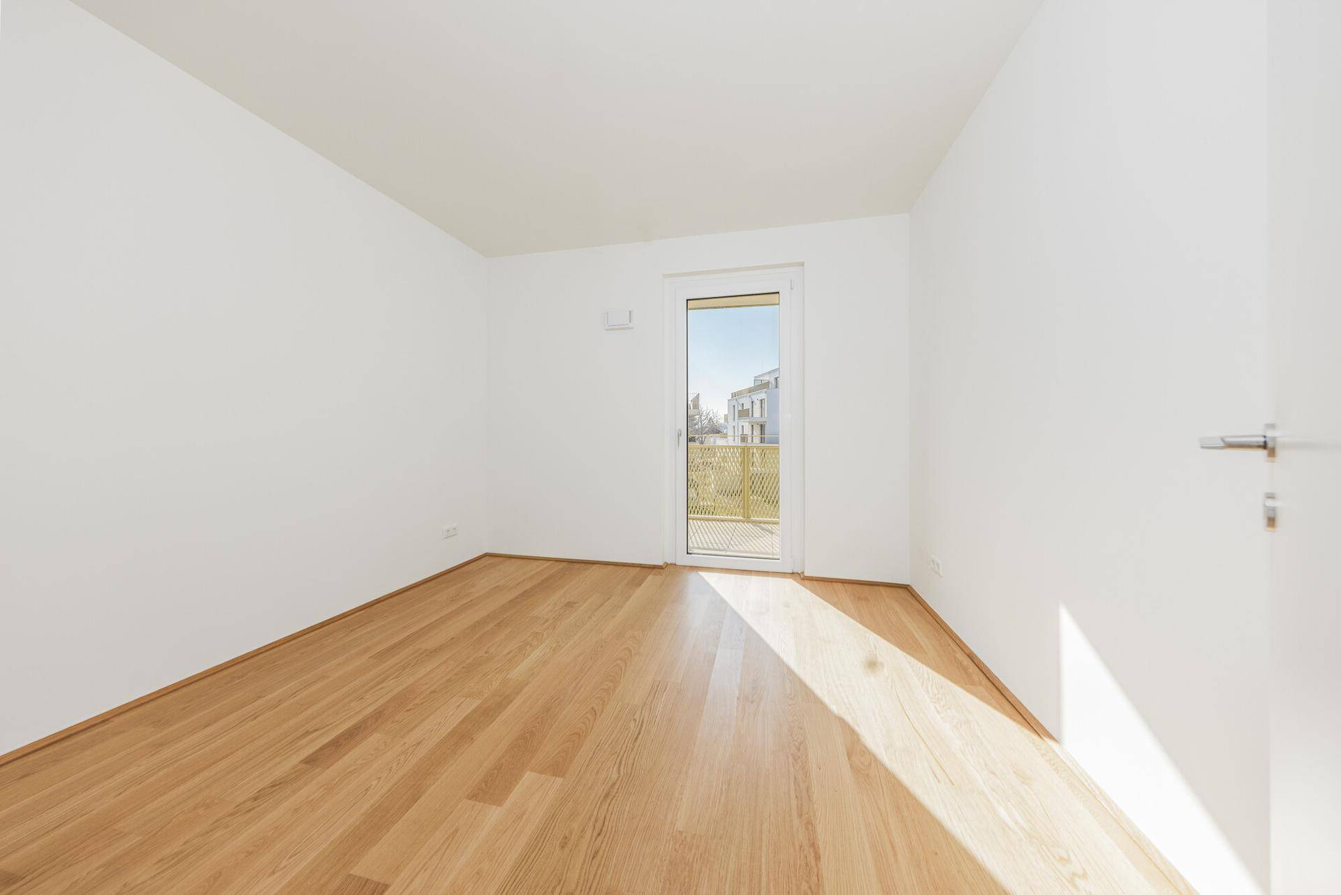 Heller, leerer Raum mit Parkettboden und Zugang zu einem Balkon, ideal für individuelle Gestaltung.