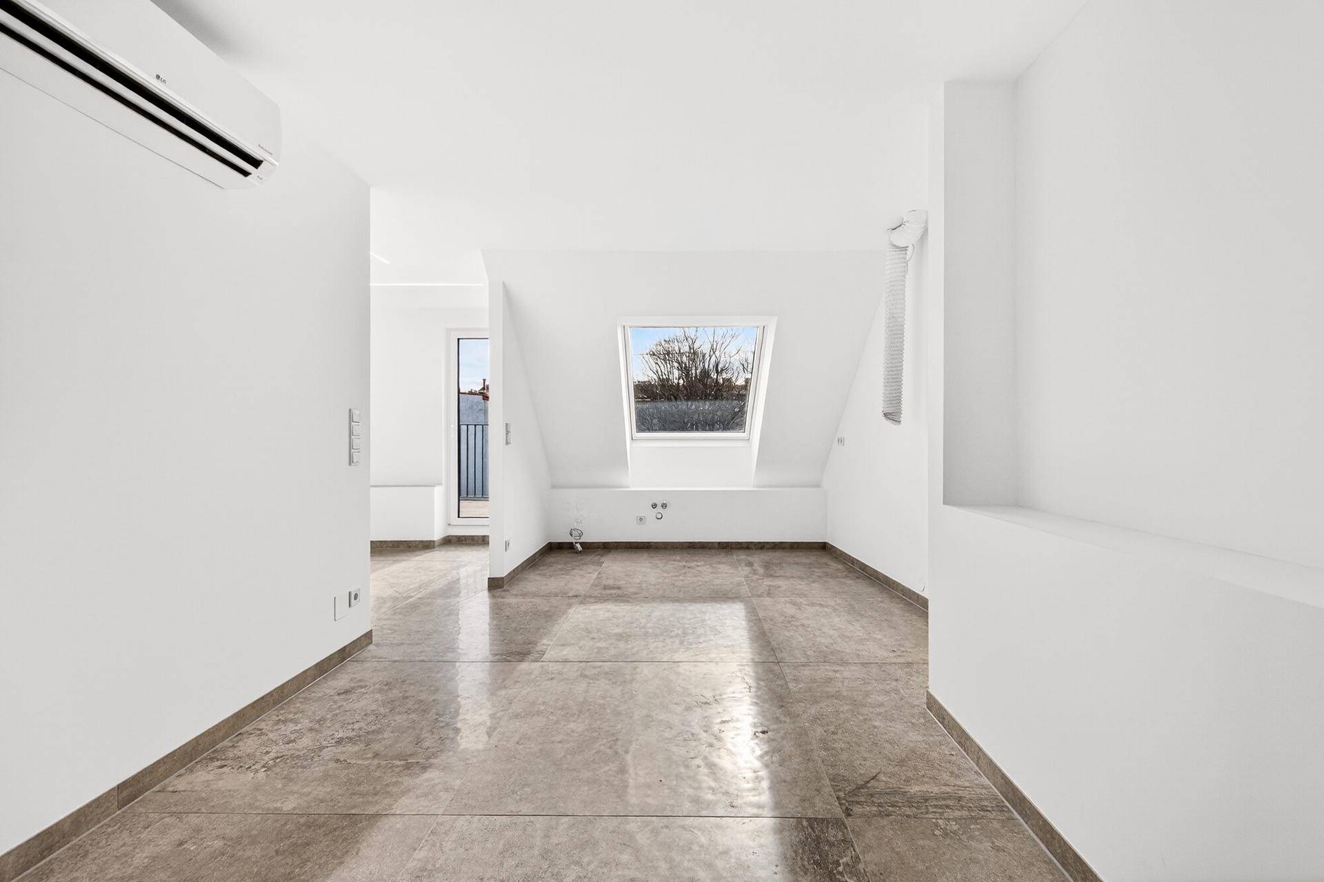 Geräumiger Dachgeschossraum mit Fliesenboden, Klimaanlage und Dachfenster.