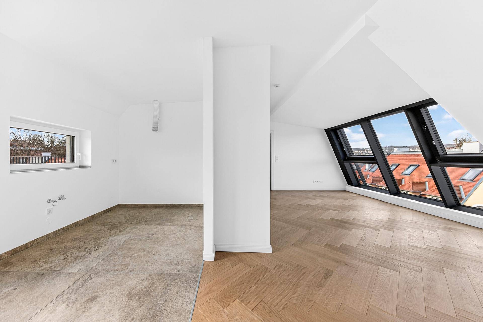 Offener Raum mit Fischgrätparkett und Fliesenboden, großen Fenstern und Blick auf die Stadt.