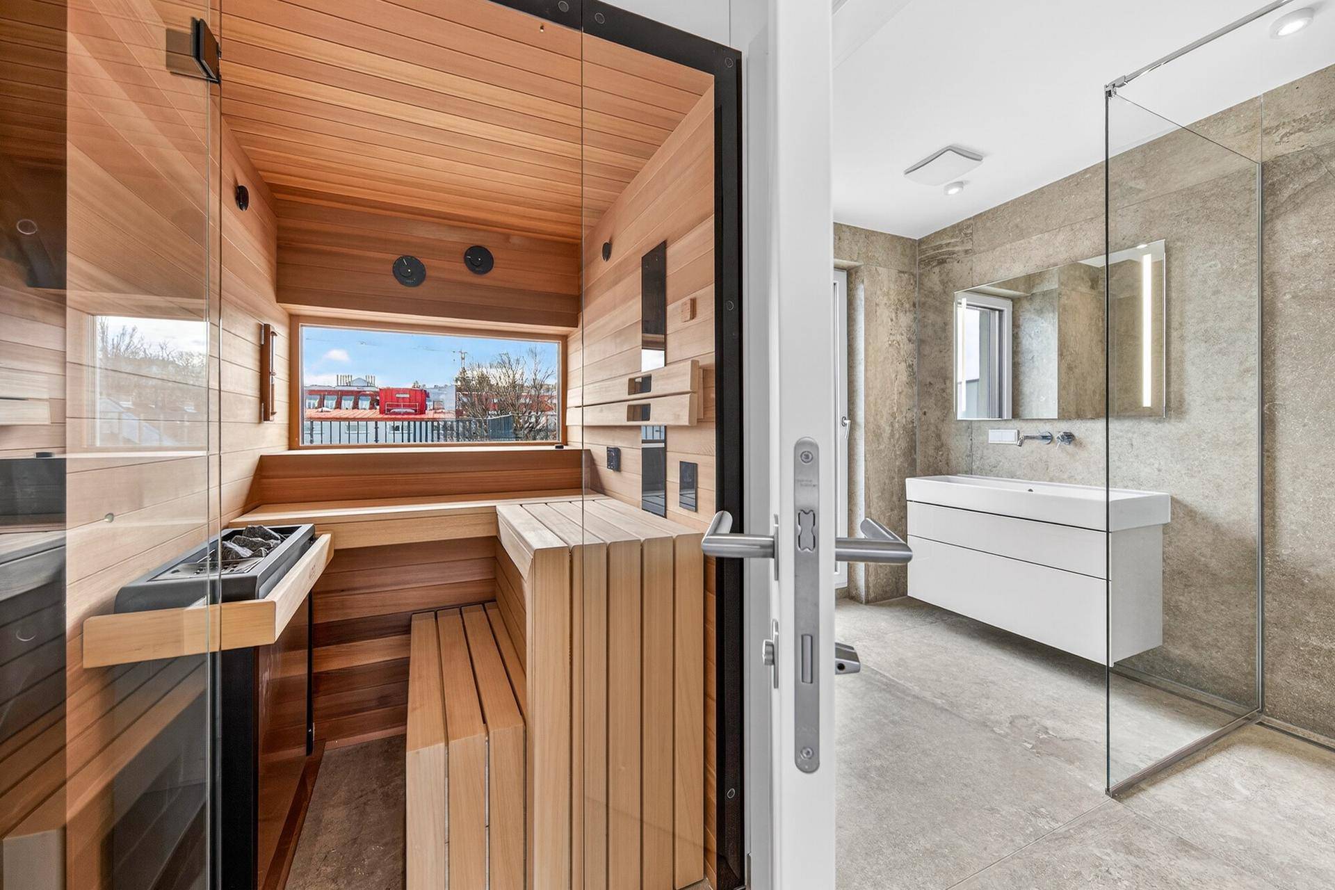 Modernes Badezimmer mit begehbarer Dusche, Einzelwaschbecken und direktem Zugang zur Sauna.