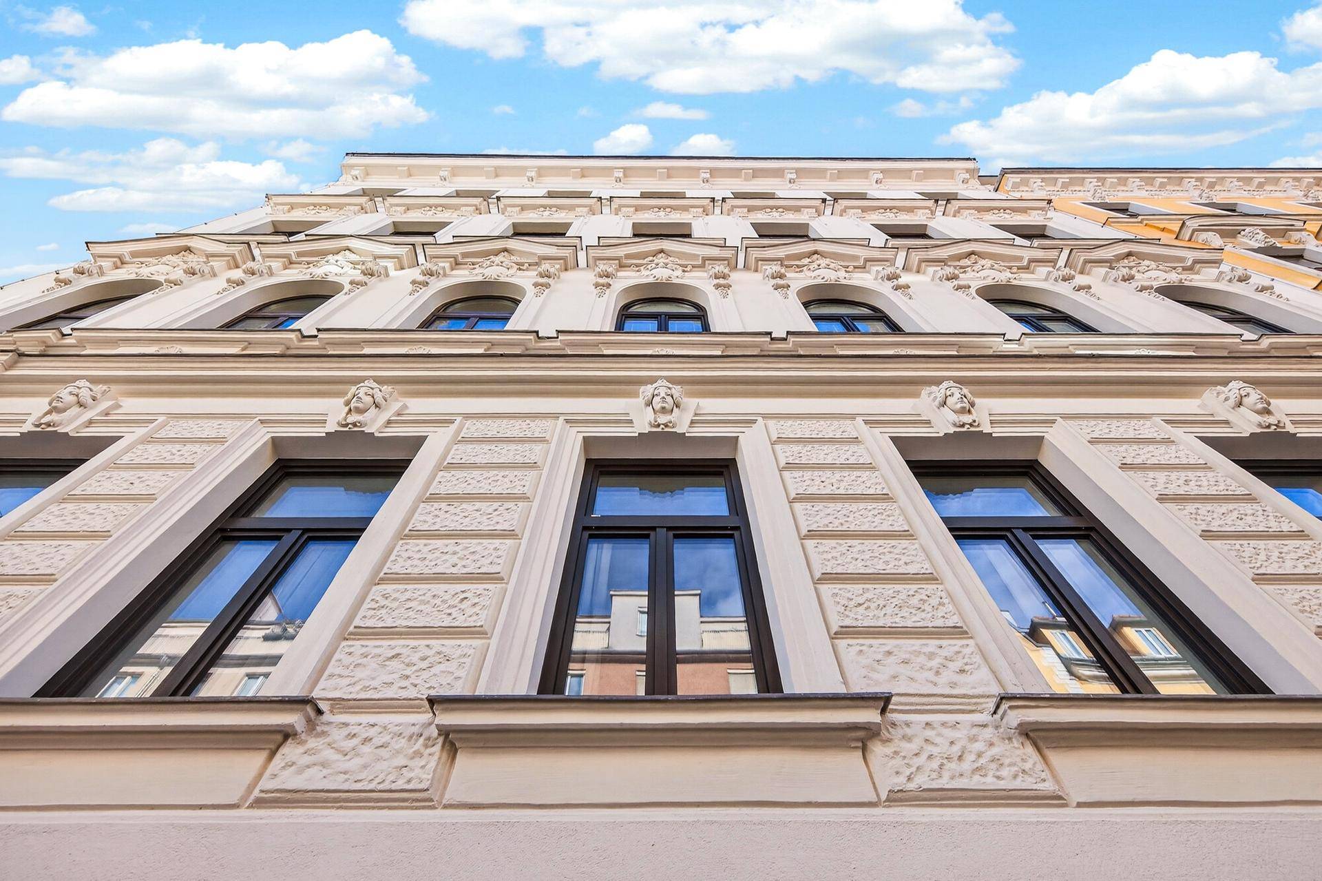 Prunkvolle Fassade eines Altbaus mit reichen Verzierungen und eleganten Bogenfenstern.