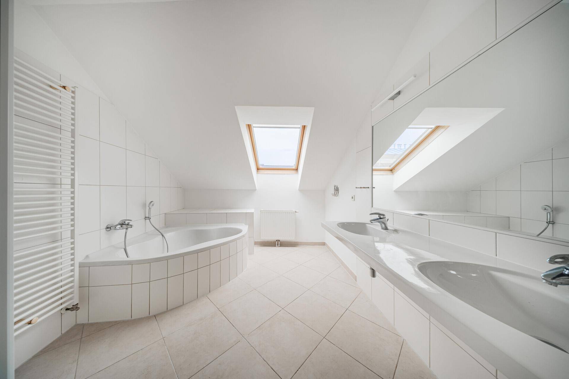 Modernes Badezimmer mit Badewanne, Doppelwaschbecken, Fliesenboden und Dachfenster.