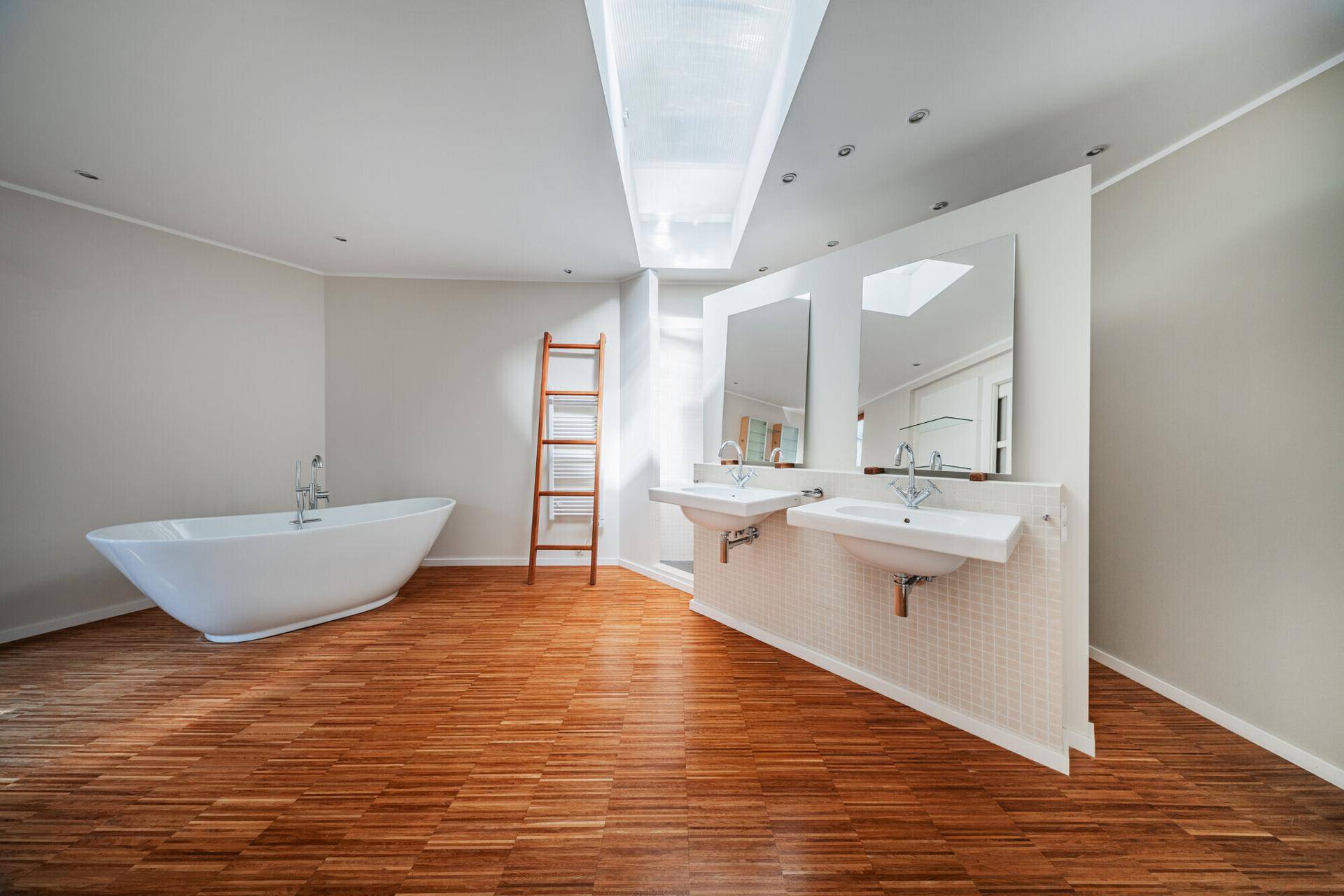 Modernes Badezimmer mit freistehender Badewanne, Doppelwaschbecken und Oberlicht für natürliches Licht.