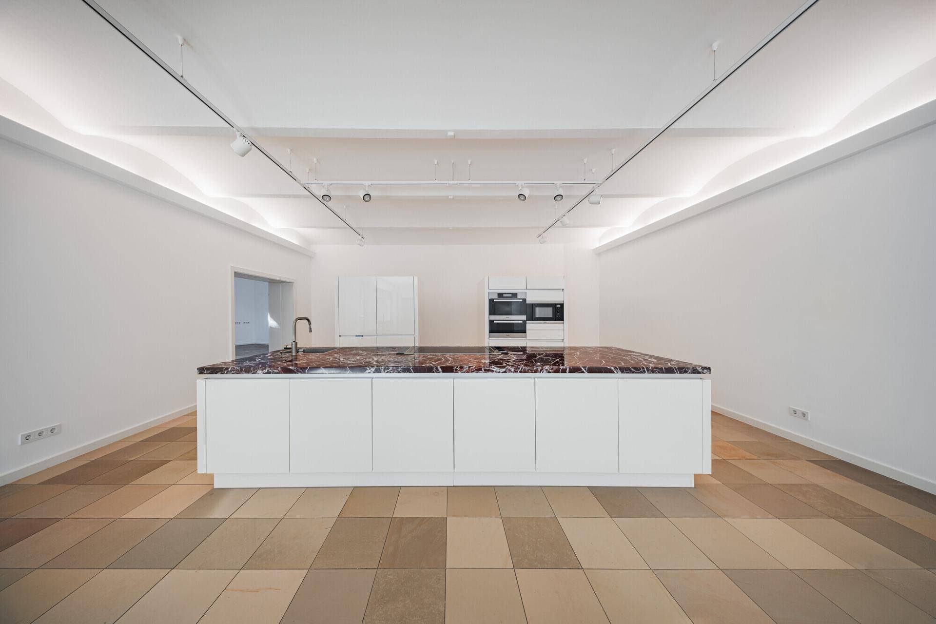 Geräumige Küche mit zentraler Kochinsel und hochwertigen Einbaugeräten in minimalistischem Design.