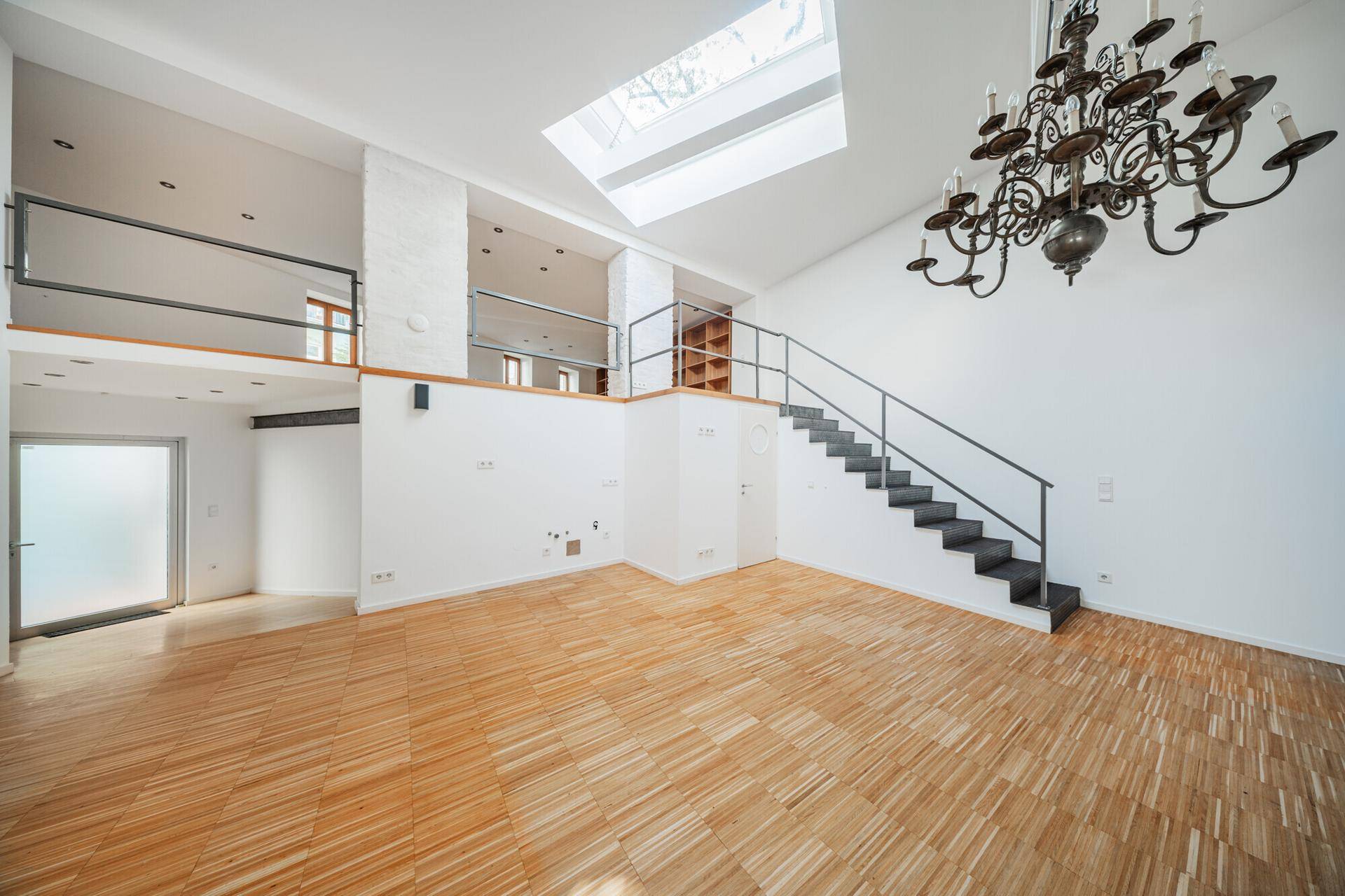 Offener Loft-Wohnbereich mit hoher Decke, Galerie, Oberlicht und Holzparkettboden.