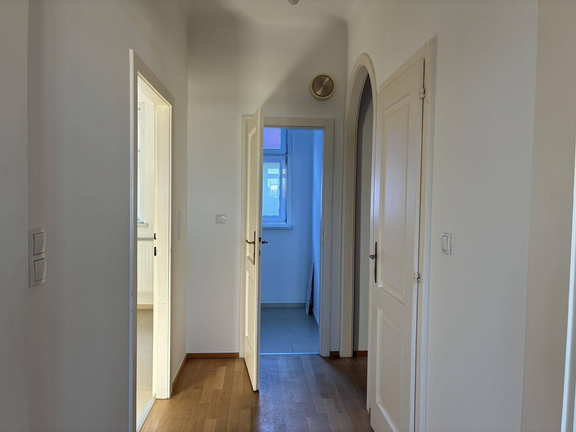 Heller Flur mit Holzfußboden und mehreren Türen, die zu den angrenzenden Räumen führen.