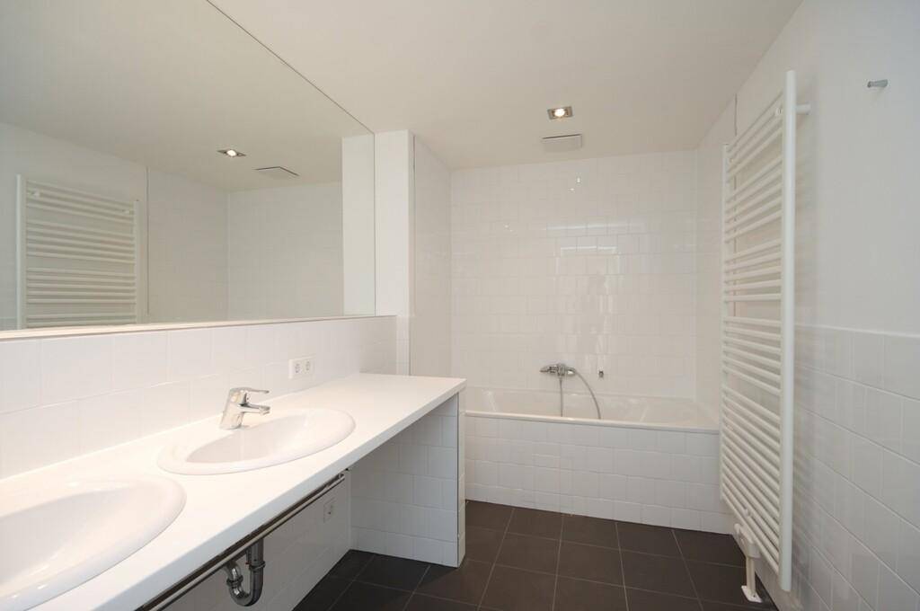 Modernes Badezimmer mit Doppelwaschbecken, Badewanne und großem Spiegel, in hellen Farben gehalten.