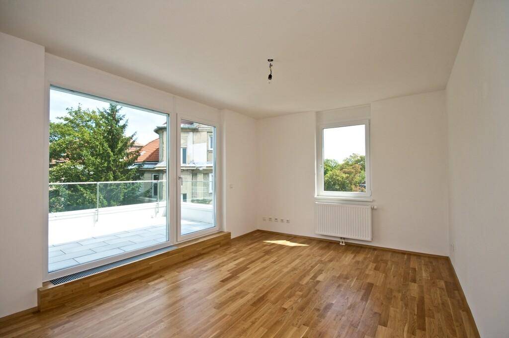 Geräumiges Zimmer mit Parkettboden und Zugang zu einer Terrasse, bietet viel natürliches Licht.