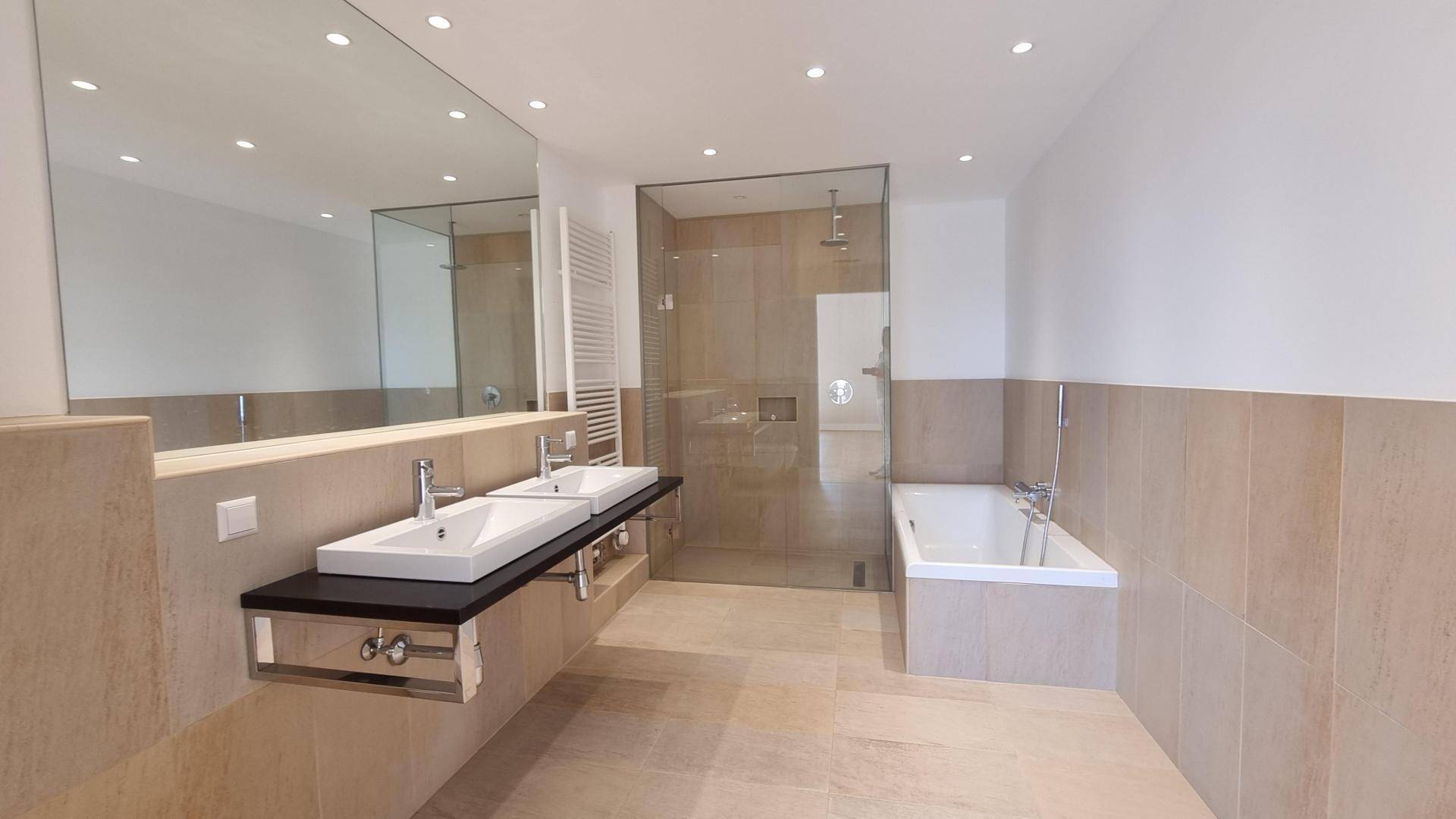 Modernes Badezimmer mit Doppelwaschbecken, großer Spiegelfläche, begehbarer Dusche und Badewanne.
