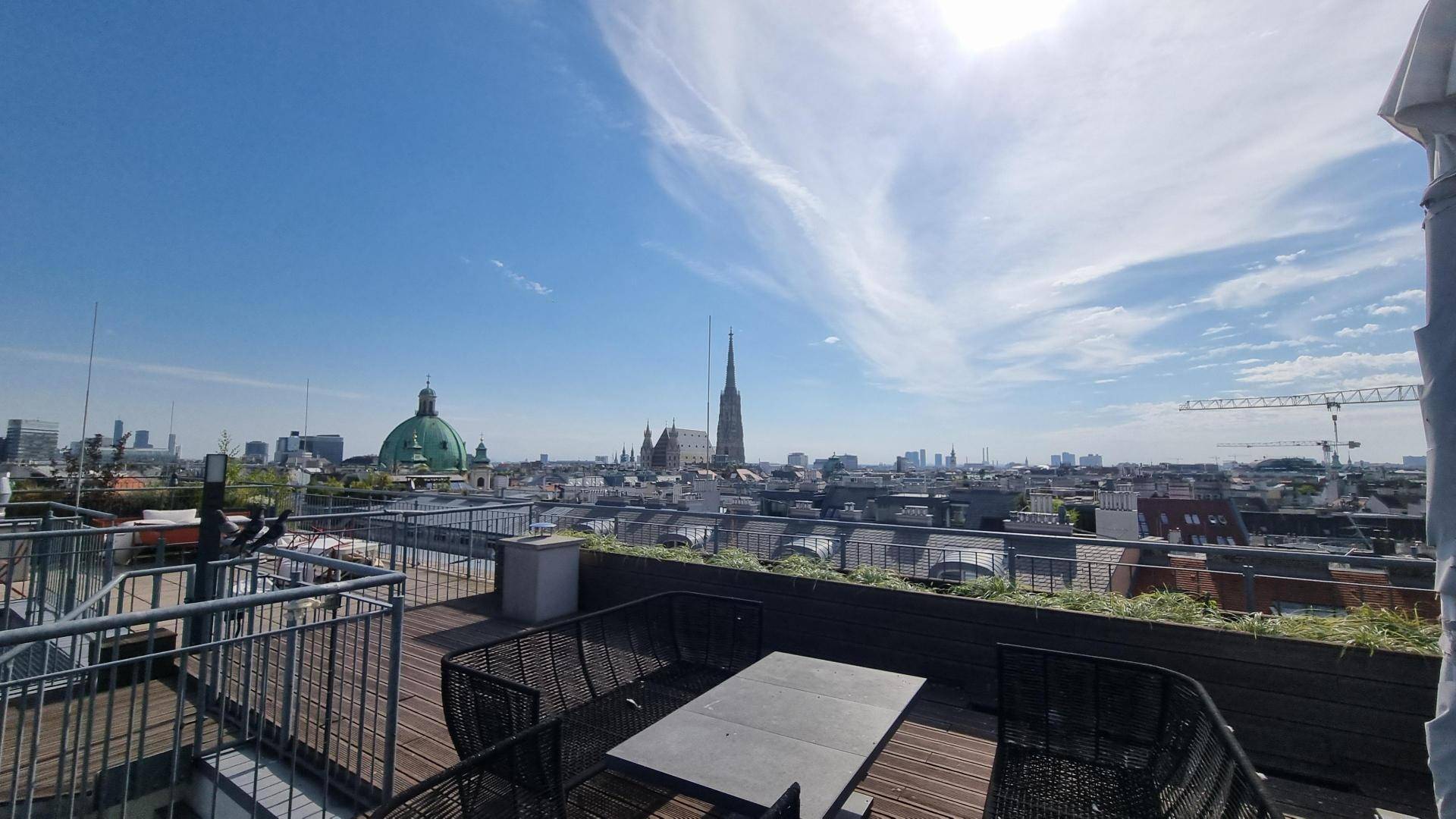 Möblierte Dachterrasse mit Holzboden und weitem Panoramablick über die Stadt.