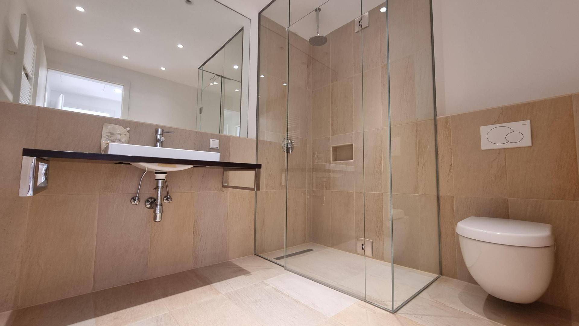 Modernes Badezimmer mit Einzelwaschbecken, begehbarer Dusche und wandhängendem WC.
