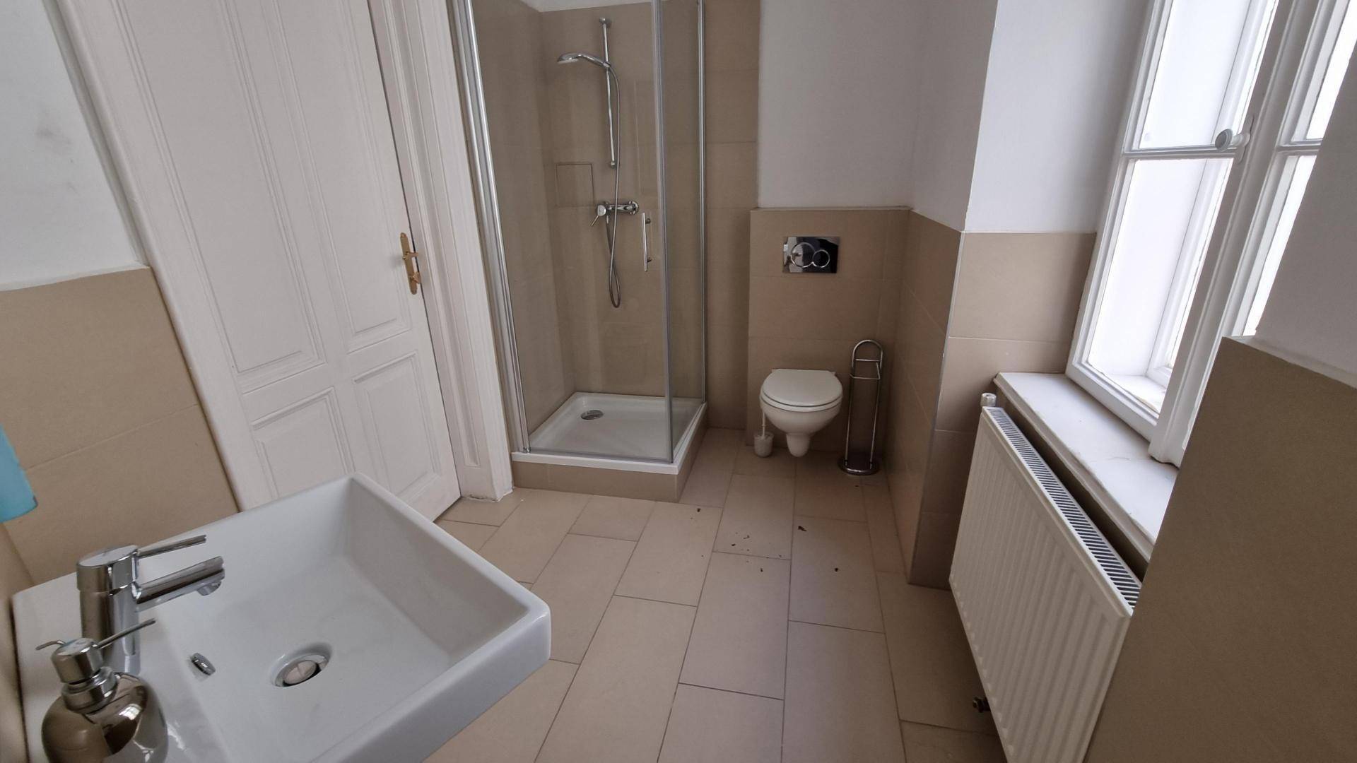 Modernes Badezimmer mit Dusche, WC, Waschbecken und Fenster für natürliche Belüftung.