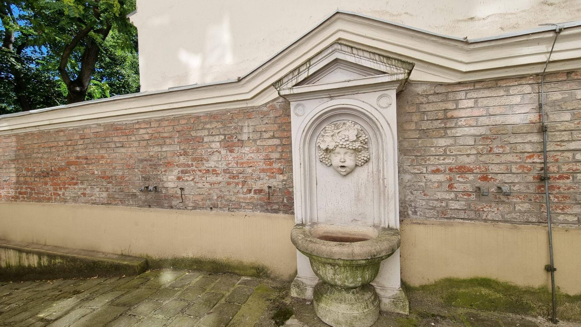 Detailansicht eines historischen Brunnens mit Skulptur in einem charmanten Innenhof.