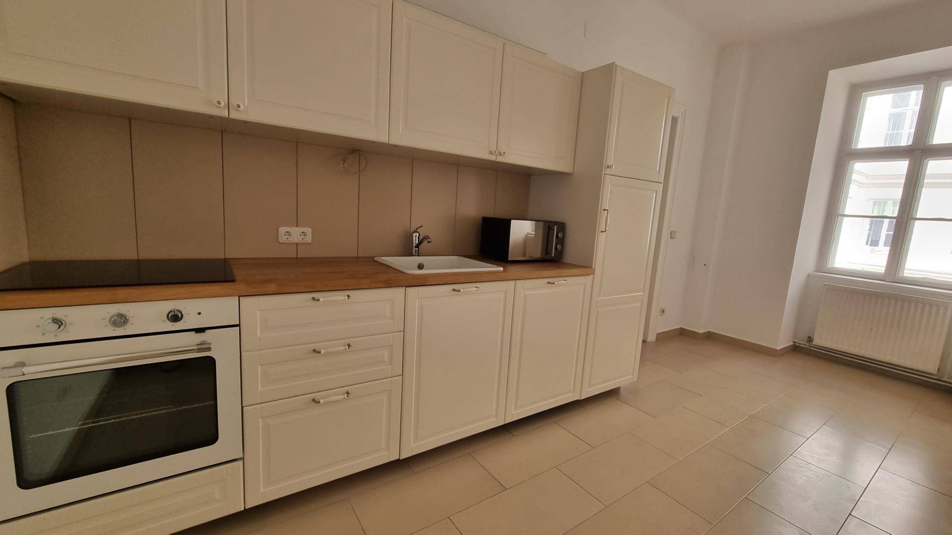 Funktionale Küche mit hellen Einbauschränken, Holztheke und modernen Geräten.