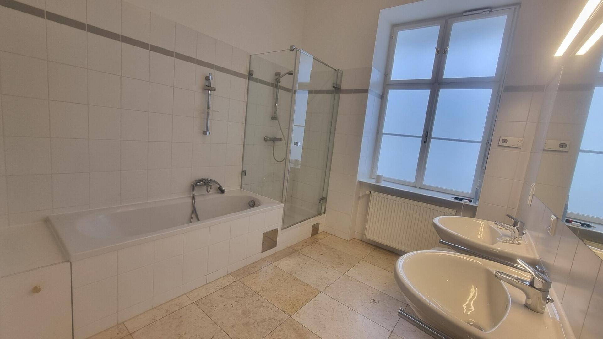 Modernes Badezimmer mit Doppelwaschbecken, Badewanne, Duschkabine und Fenster.