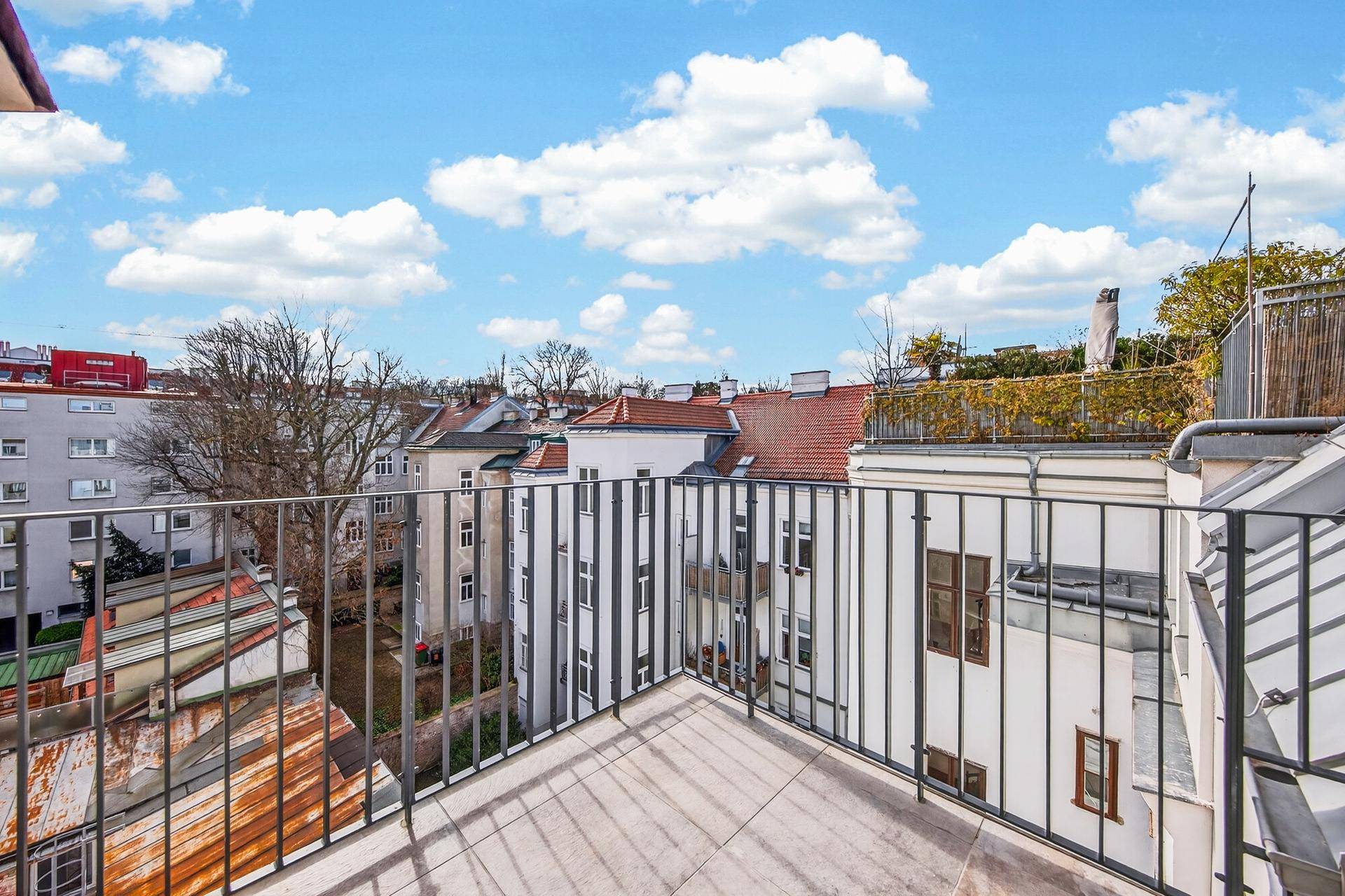 Geräumiger Balkon mit Blick über die Dächer der Stadt und umliegende Gebäude.