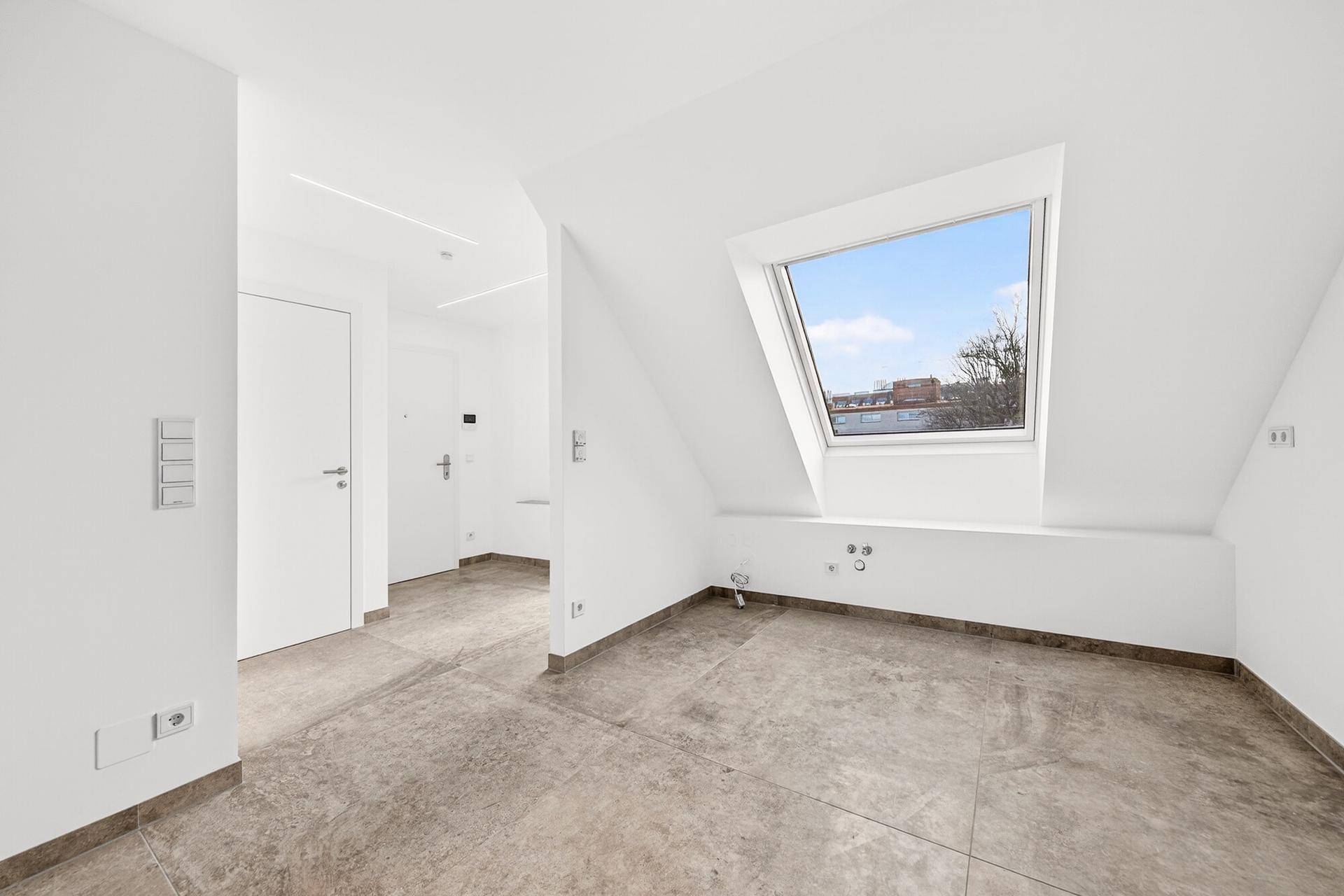 Heller Eingangsbereich im Dachgeschoss mit Fliesenboden und einem großen Dachfenster.
