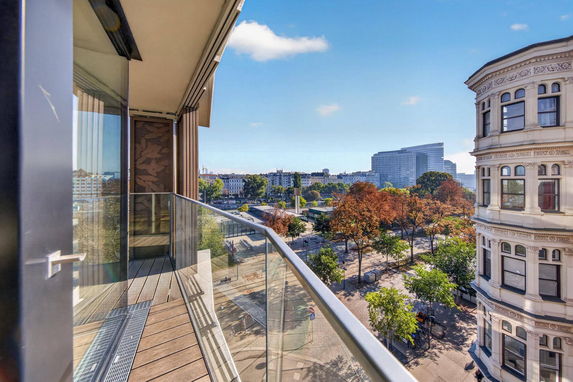 Moderner Balkon mit Glasbrüstung und weitem Blick über die Stadt und historische Gebäude.