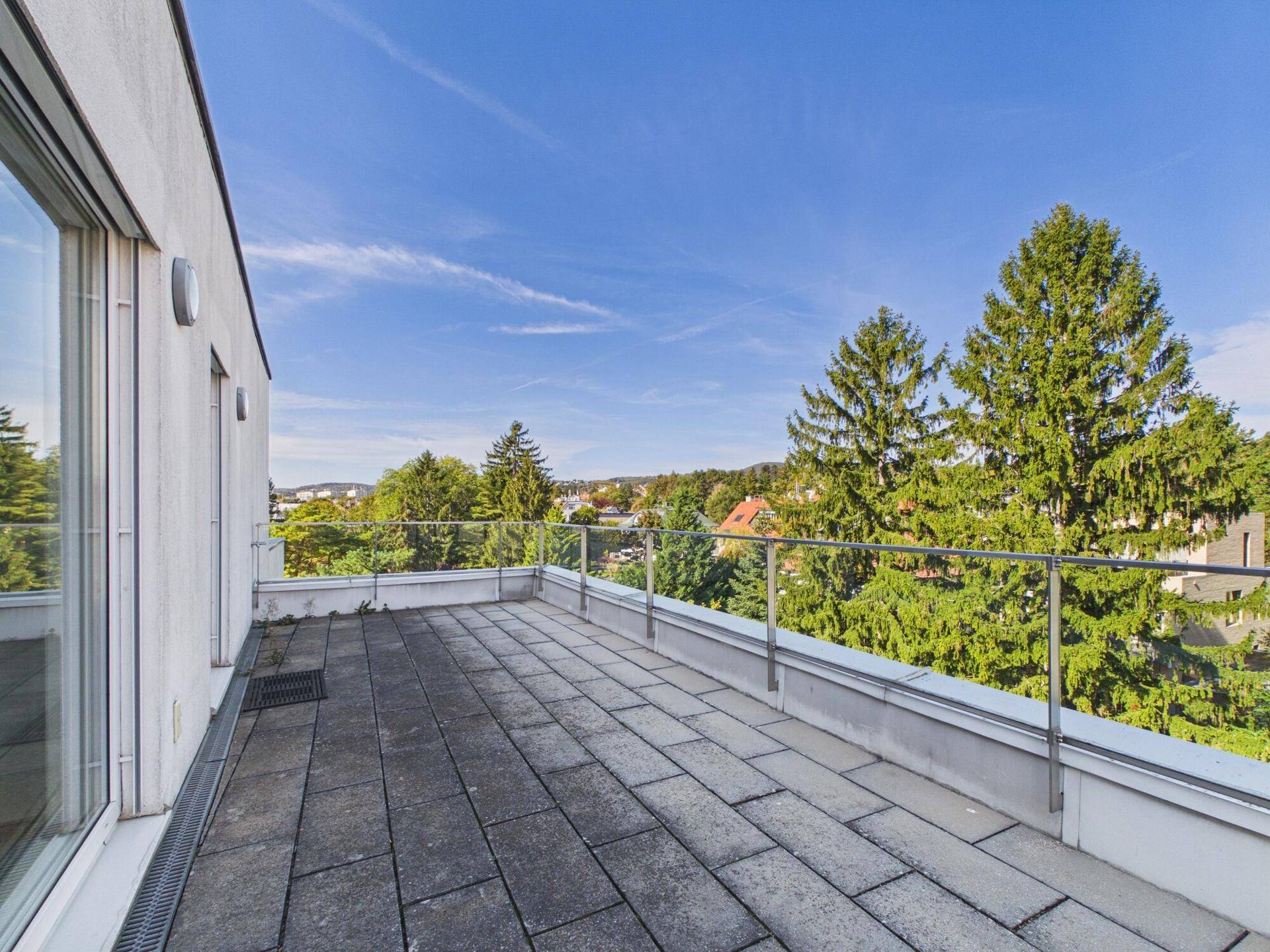 Geräumige Dachterrasse mit Steinplatten und weitem Blick über die grüne Umgebung.