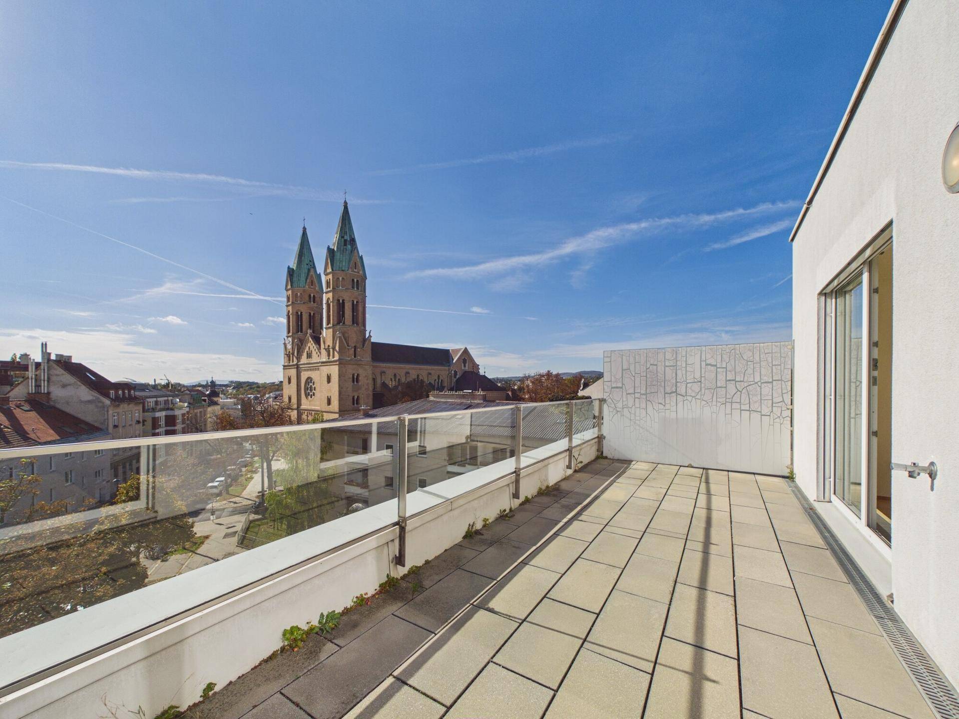 Weitläufige Dachterrasse mit Stadtblick und Blick auf eine historische Kirche.