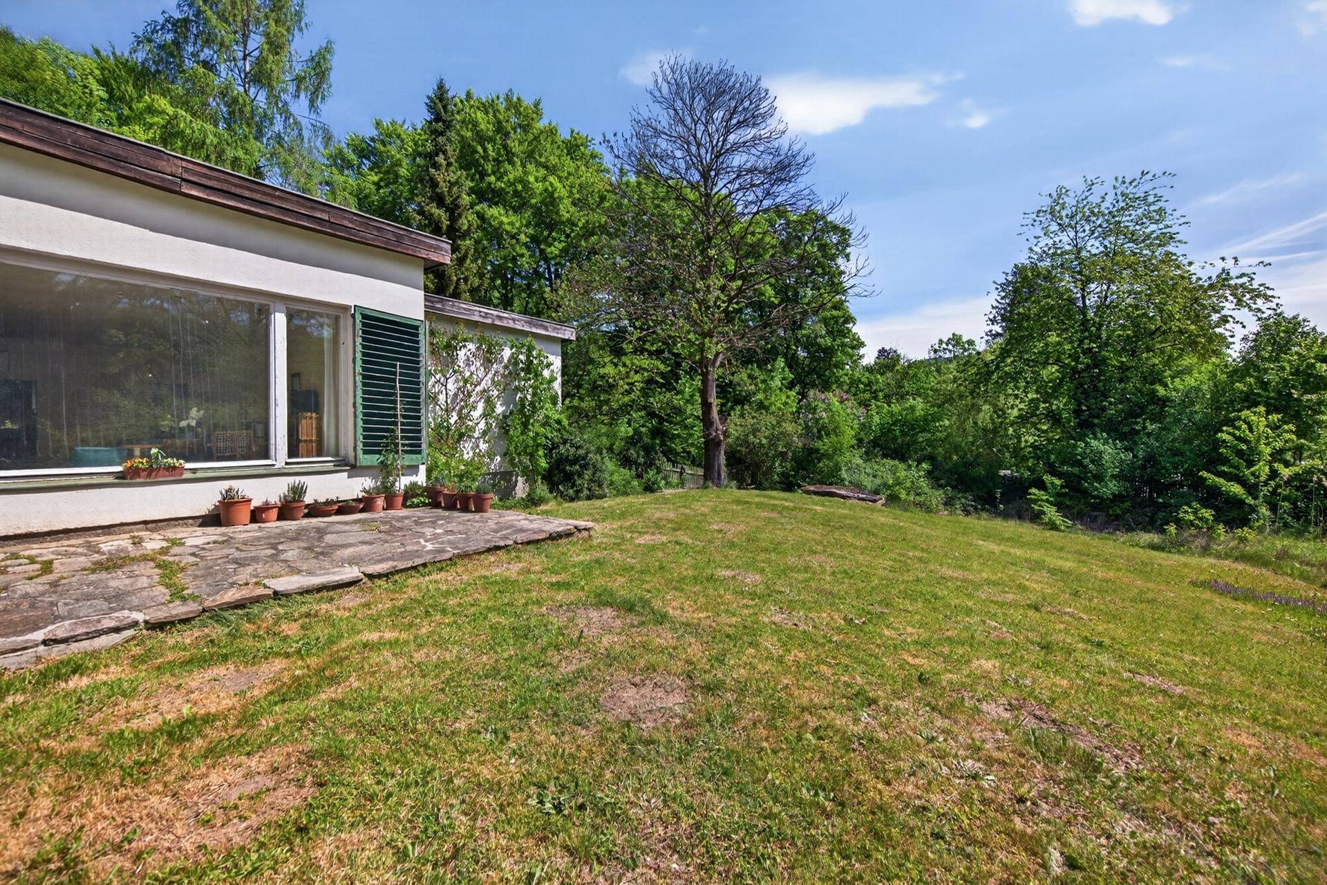 Große Rasenfläche neben dem Haus mit Blick auf die umliegende grüne Natur.