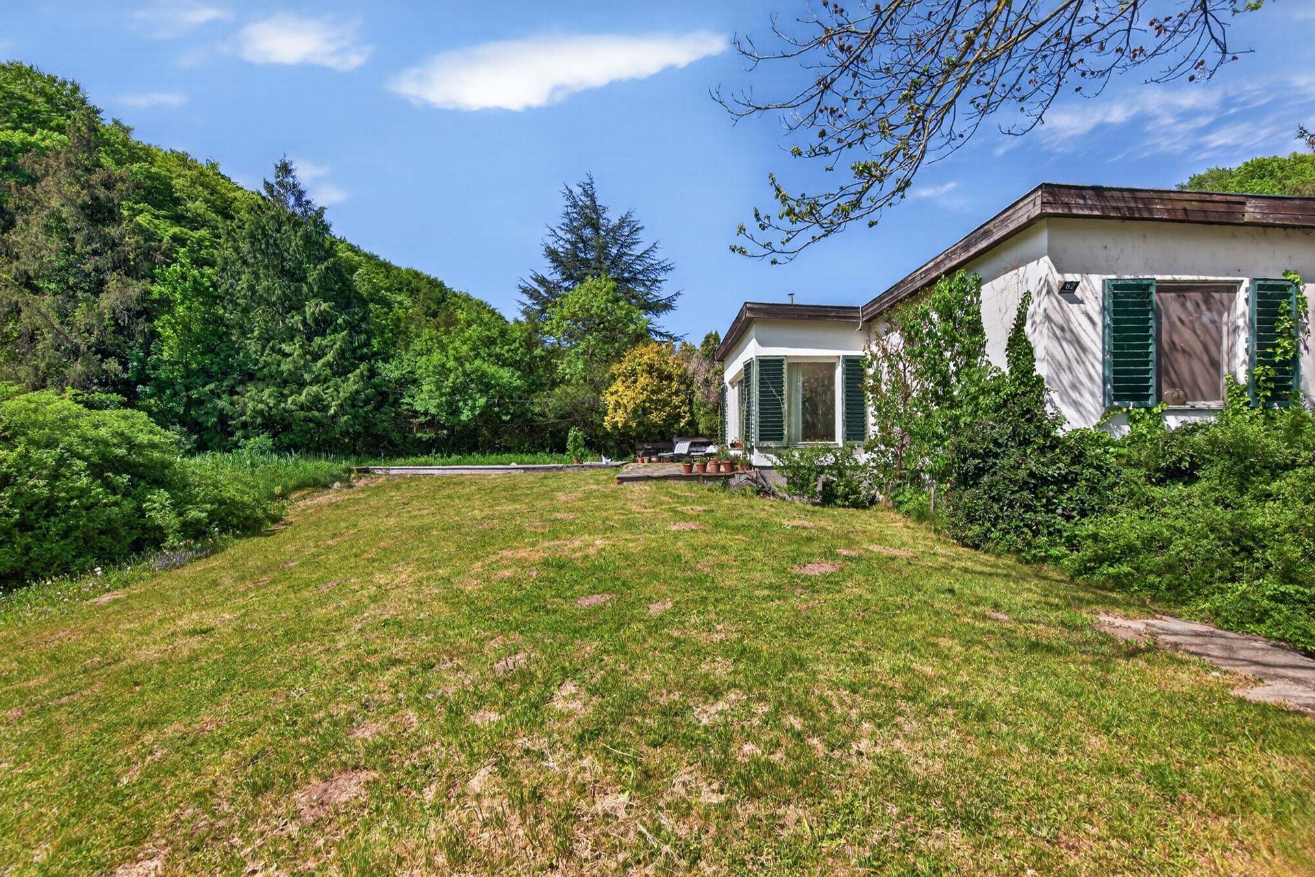 Weitläufiger Gartenbereich mit Rasen und üppiger Vegetation rund um das Haus.