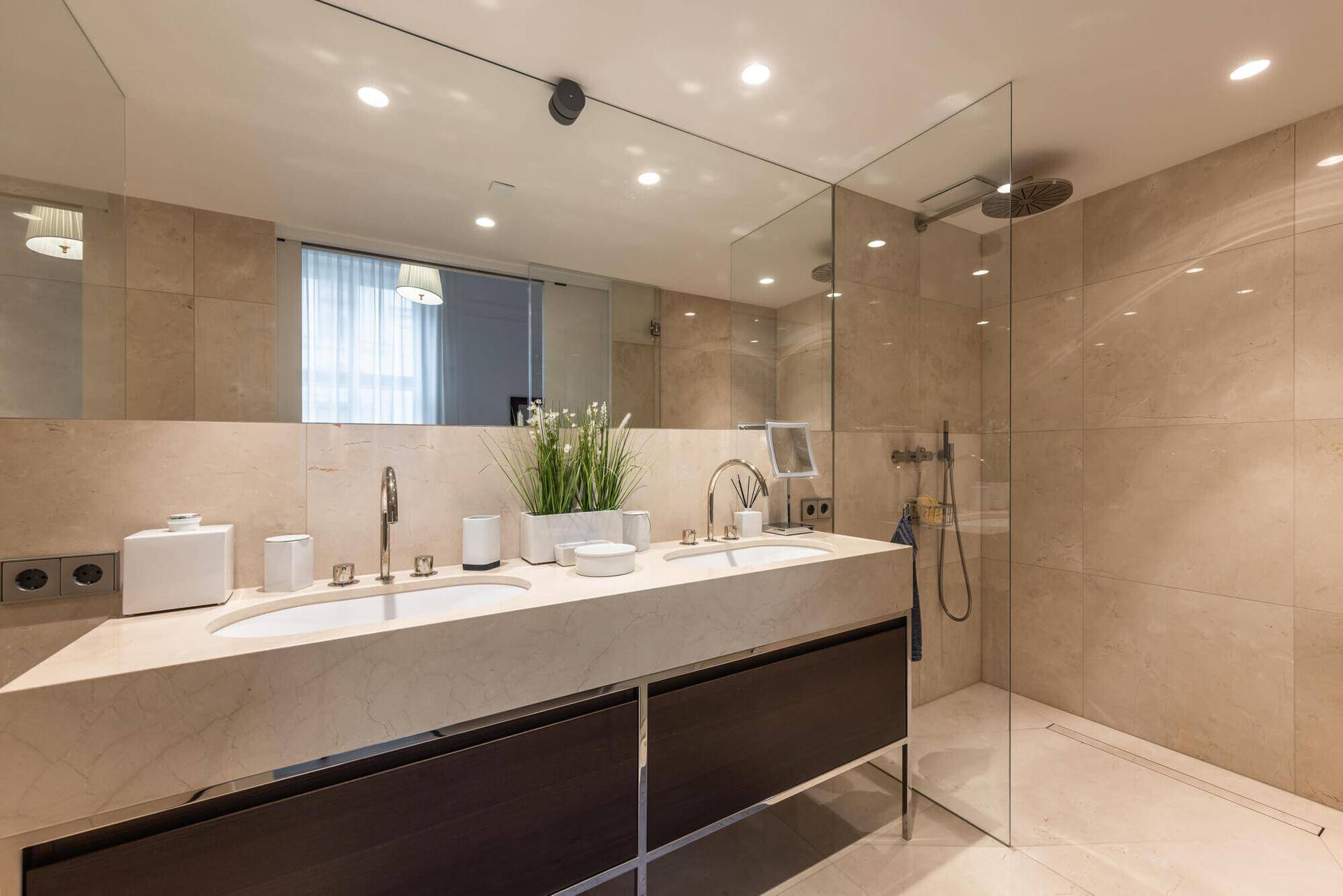 Modernes Badezimmer mit Doppelwaschbecken, begehbarer Dusche und beigefarbenen Fliesen.