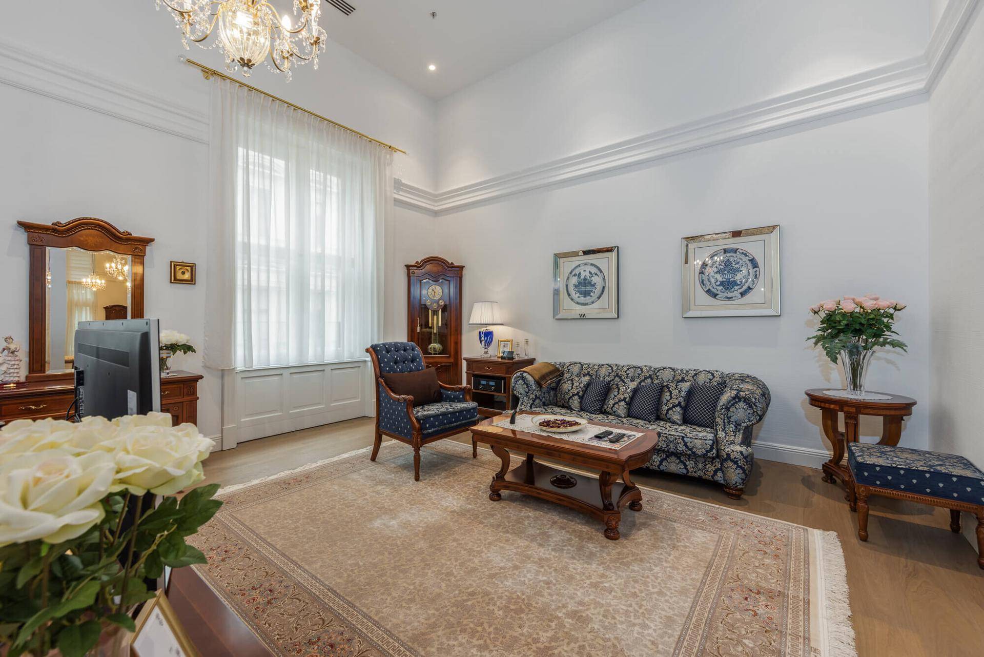 Gemütliches Wohnzimmer mit klassischem Sofa, Teppich und eleganten Holzmöbeln.