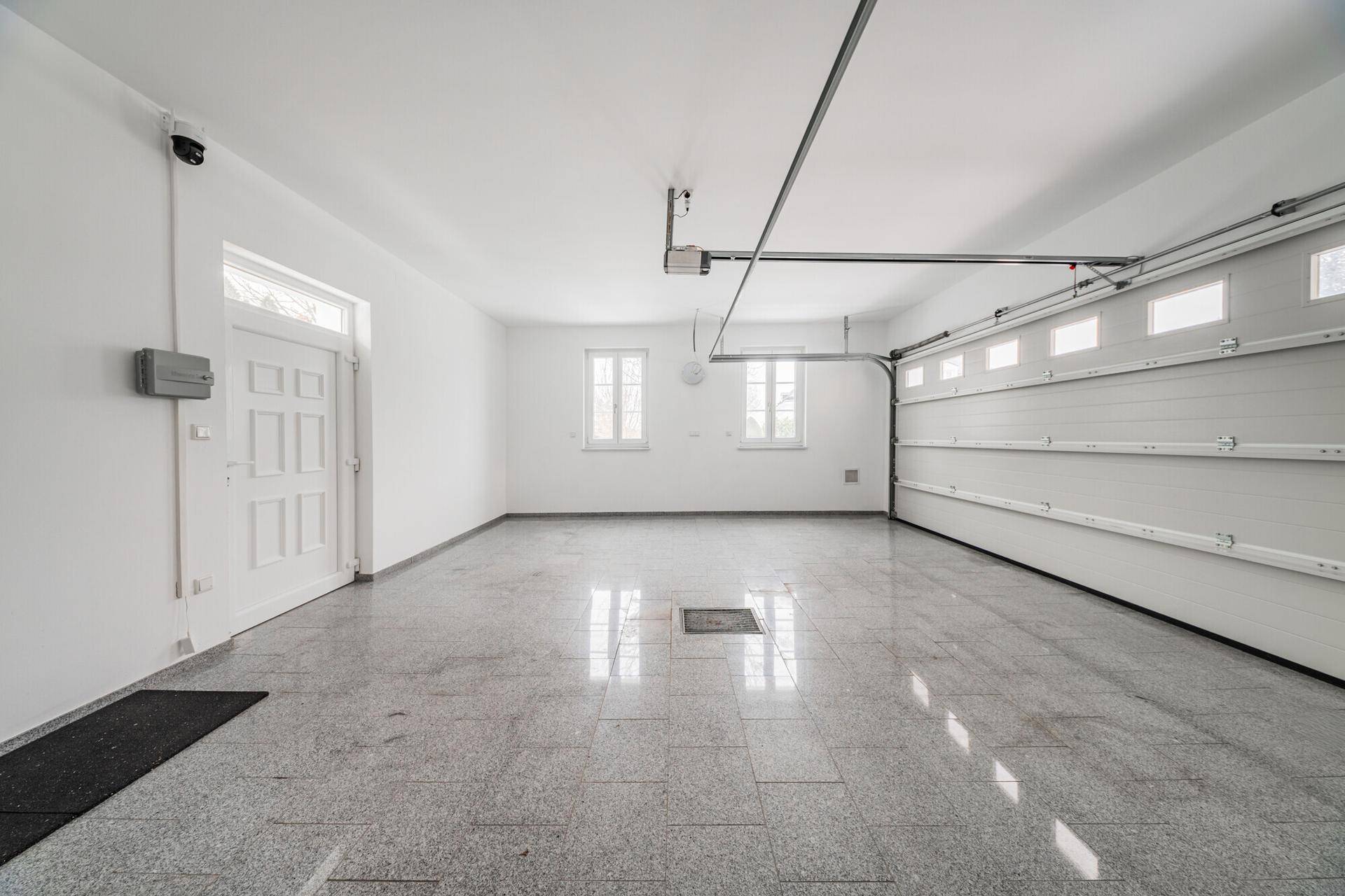Geräumige Garage mit Fliesenboden, automatischem Tor und ausreichend Platz für Fahrzeuge.