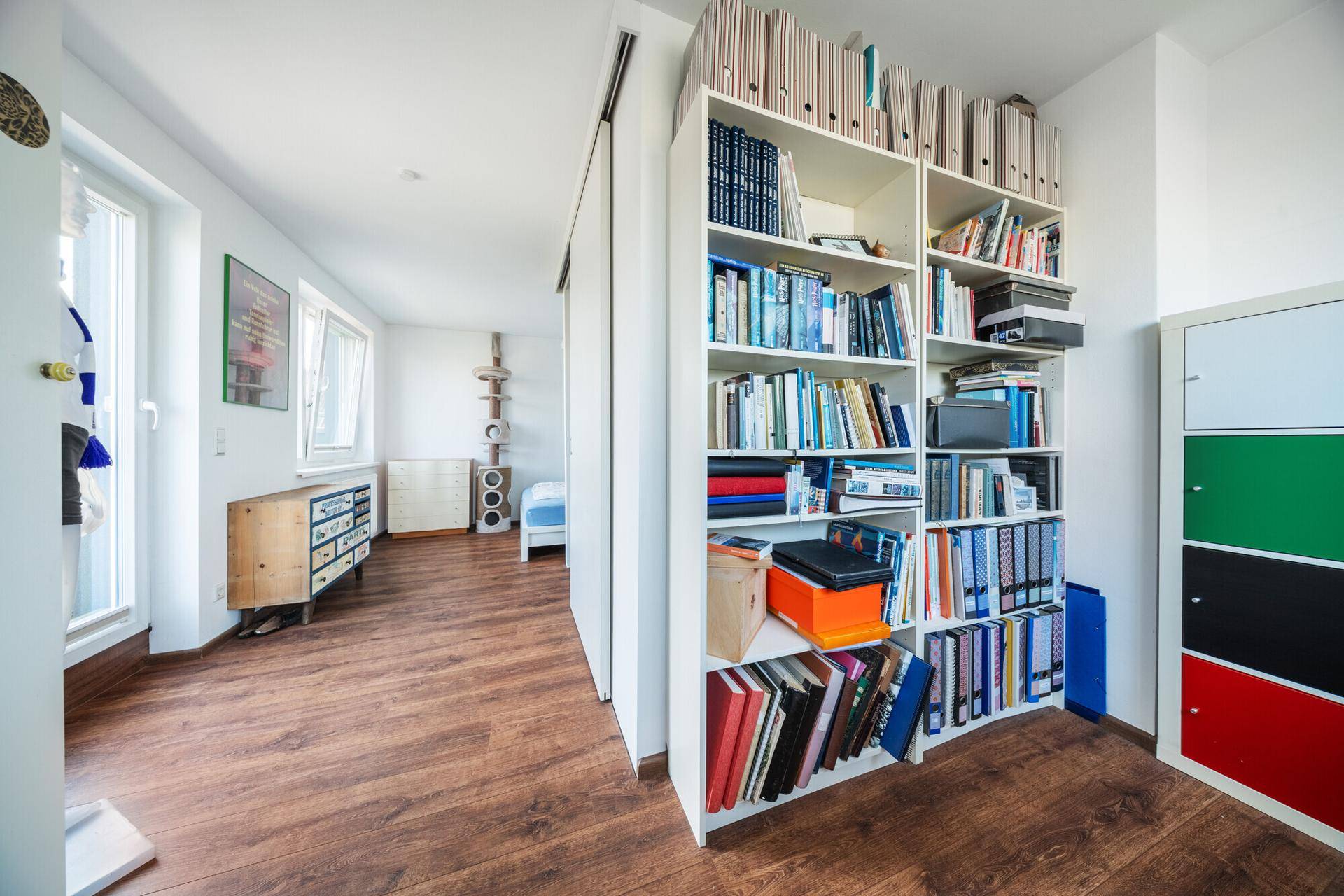 Heller Flur mit Bücherregal, Holzboden und Blick in angrenzende Räume.