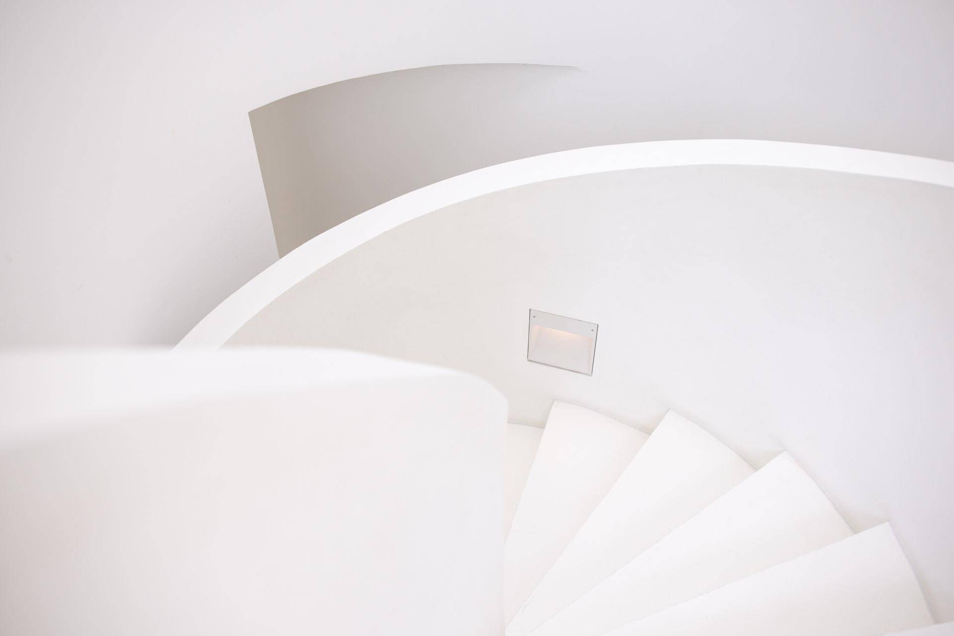 Detailaufnahme einer eleganten, geschwungenen weißen Treppe mit minimalistischem Design.