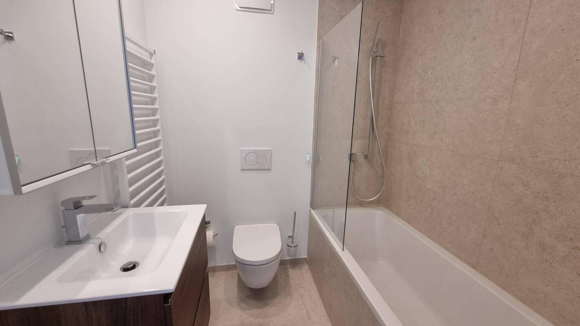 Modernes Badezimmer mit Badewanne, Dusche, WC, Waschbecken und beheiztem Handtuchhalter.