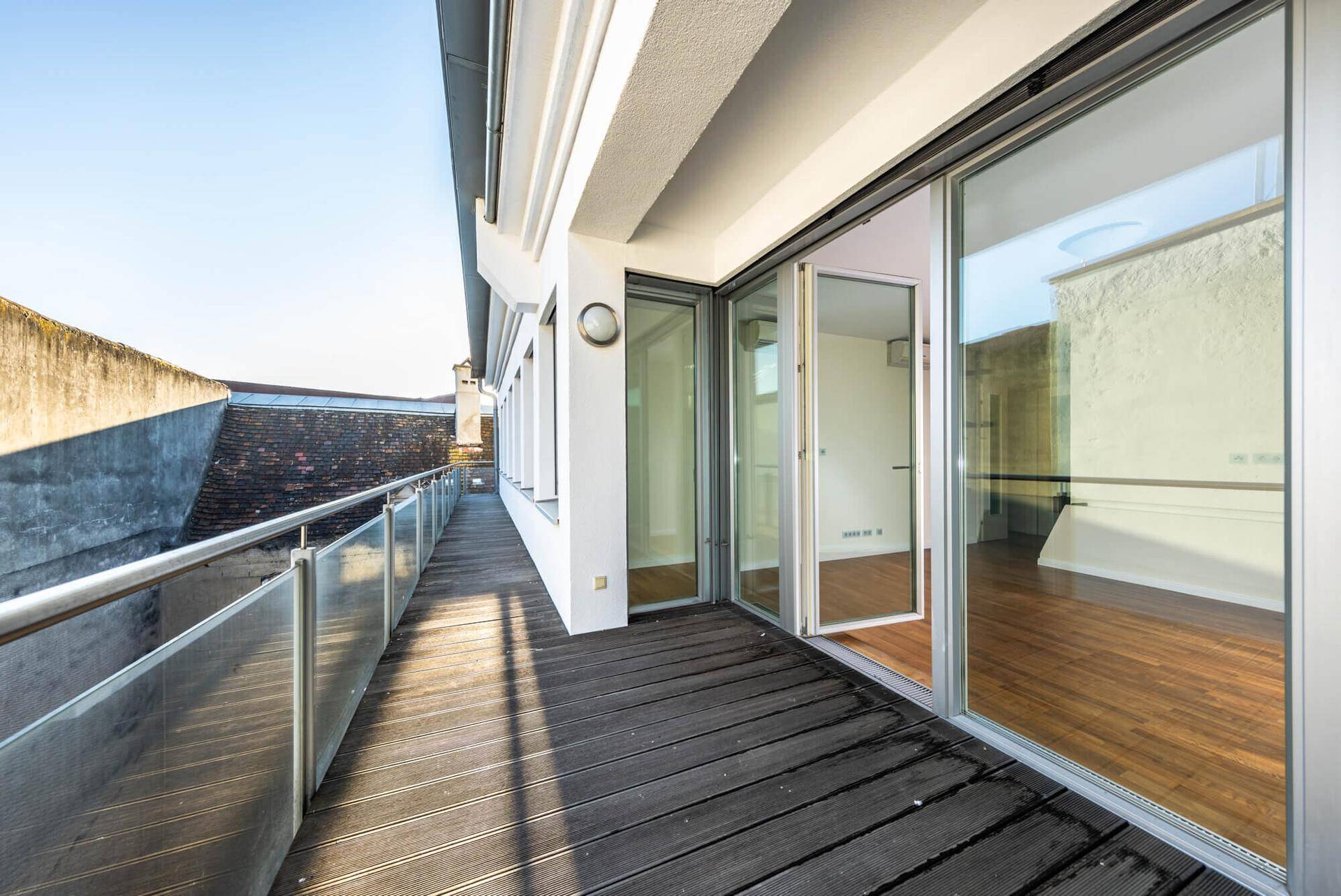 Geräumiger Balkon mit Holzdeck und großen Schiebetüren, die viel Licht in die Innenräume lassen.