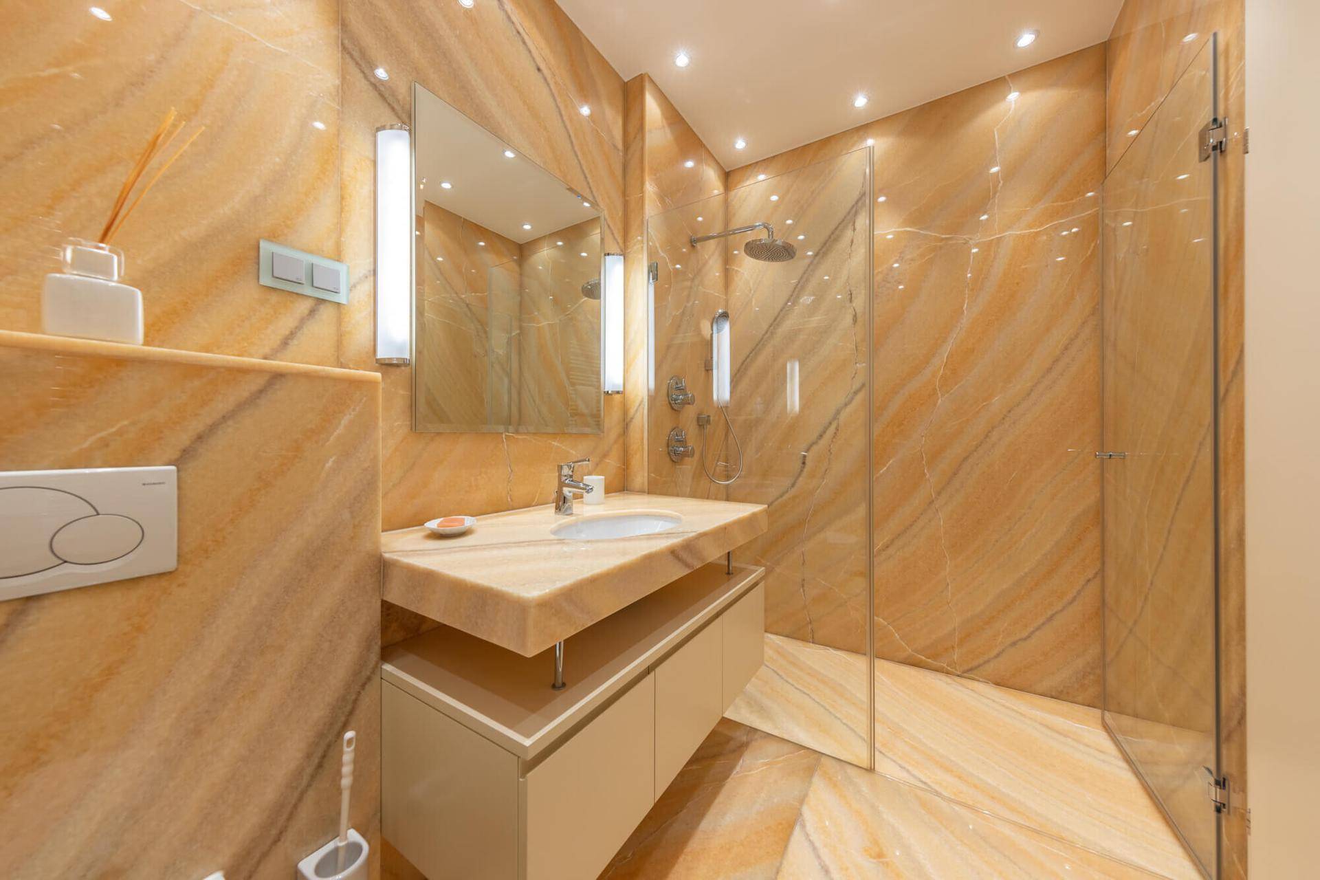 Modernes Badezimmer mit luxuriösen Marmorfliesen, ebenerdiger Dusche und elegantem Waschtisch.