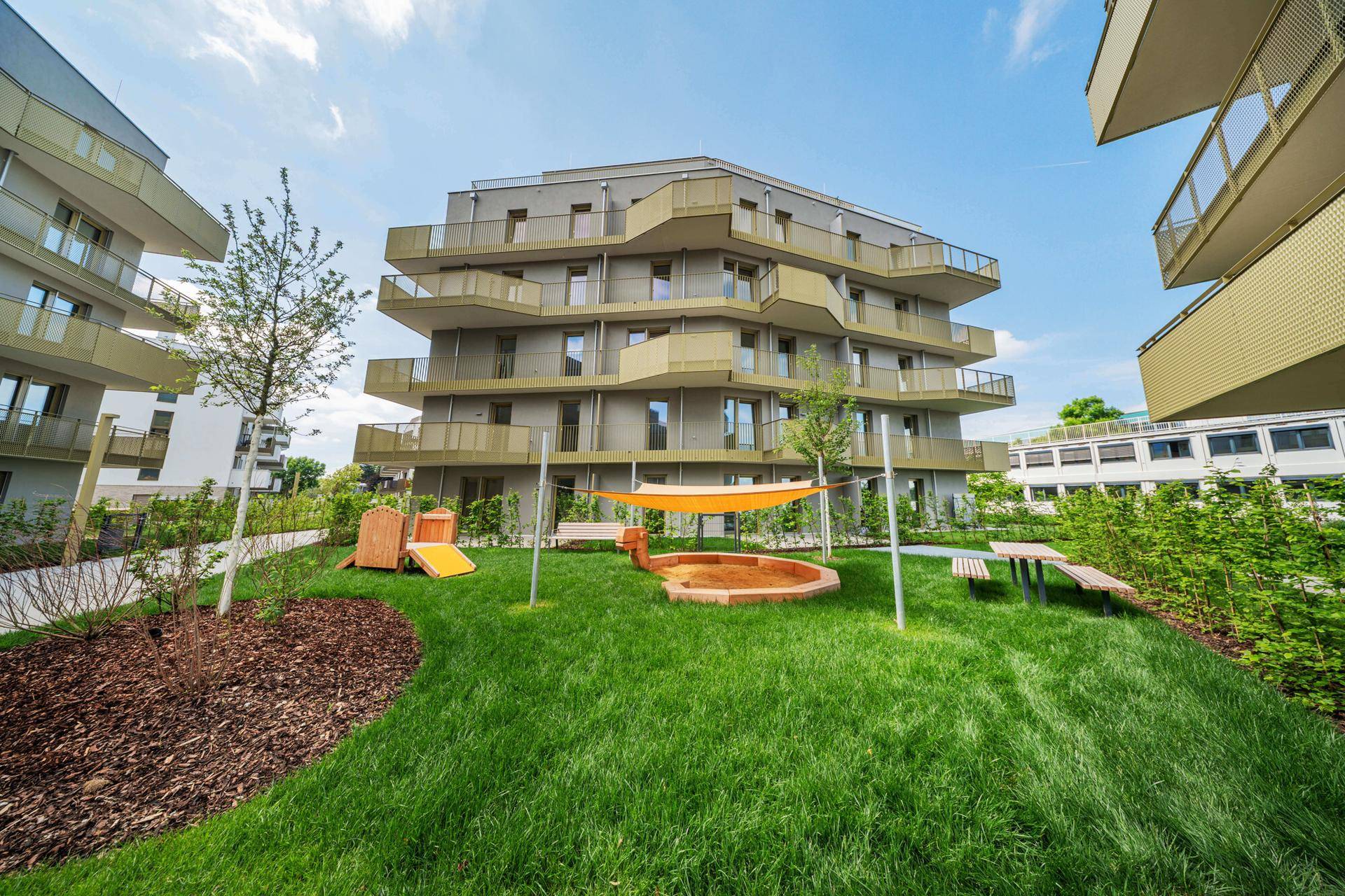 Moderne Wohnanlage mit Spielplatz und Grünflächen, umgeben von zeitgenössischer Architektur.