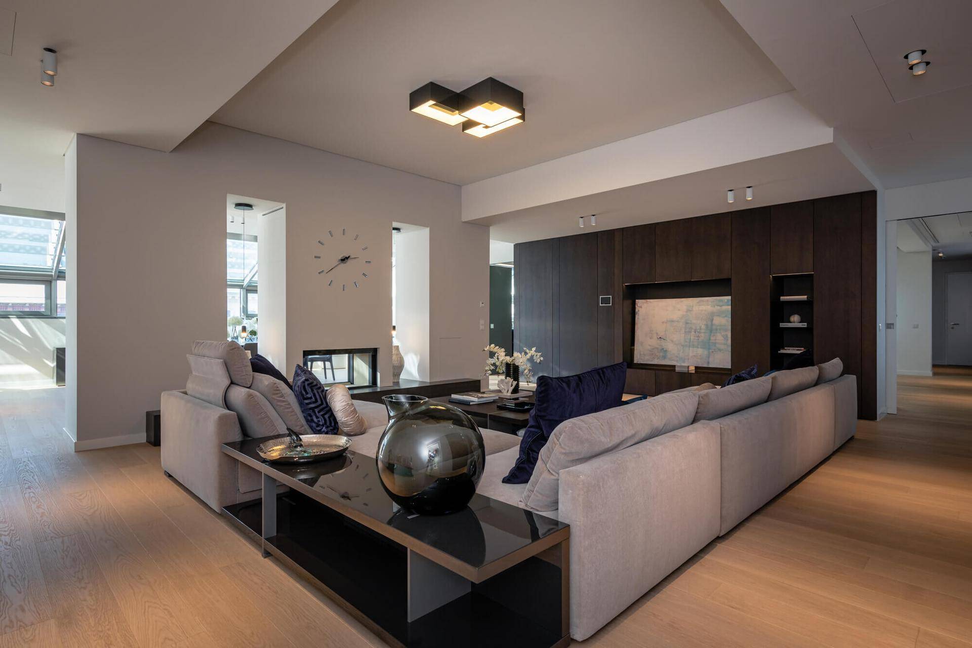 Modernes Wohnzimmer mit großem Sofa, Holzboden und integriertem Kamin, ideal für entspannte Abende.